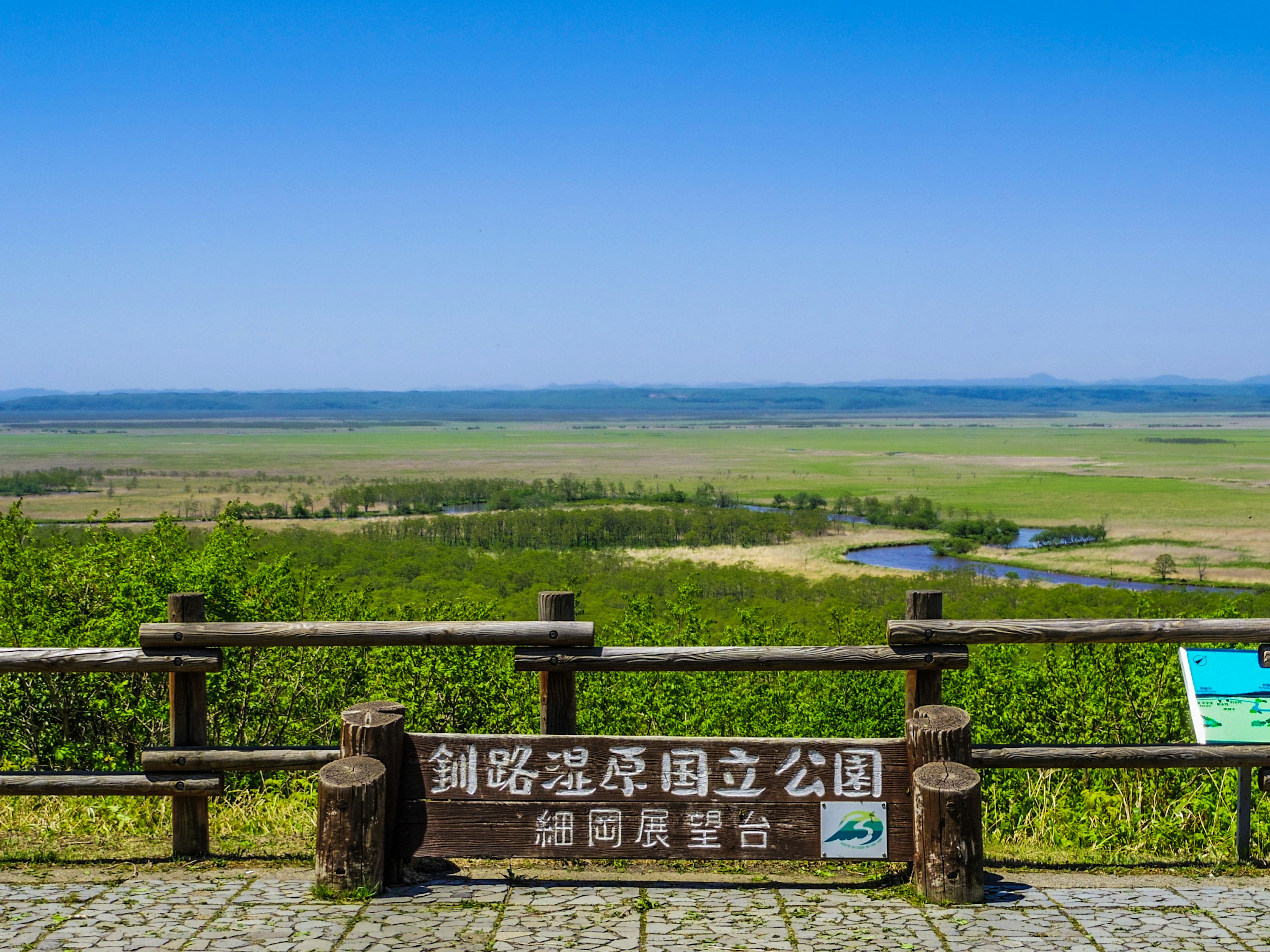 Viewpoint sign overlooking vast grasslands and a blue sky