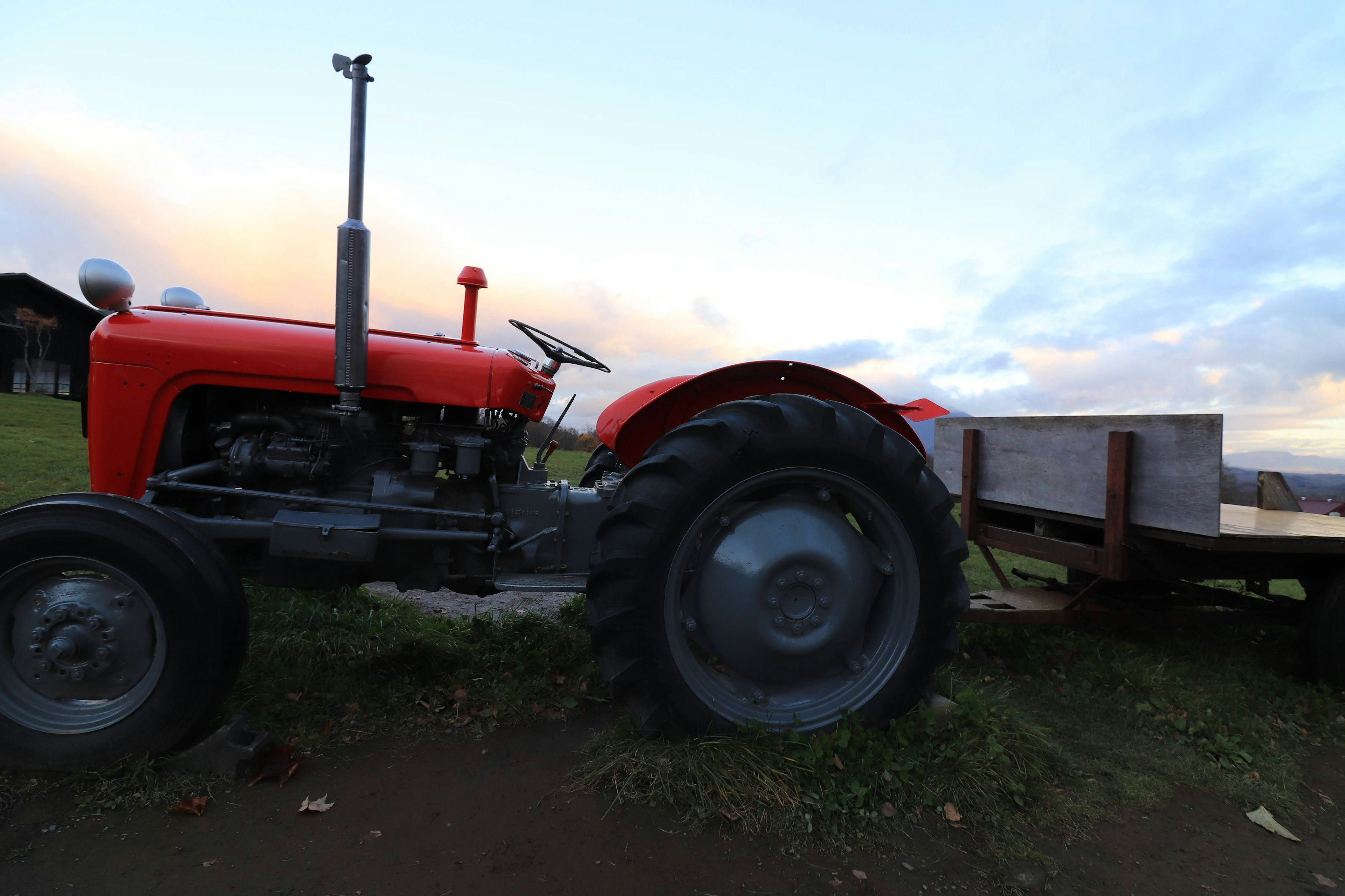 Red tractor beside a wooden trailer in an outdoor setting