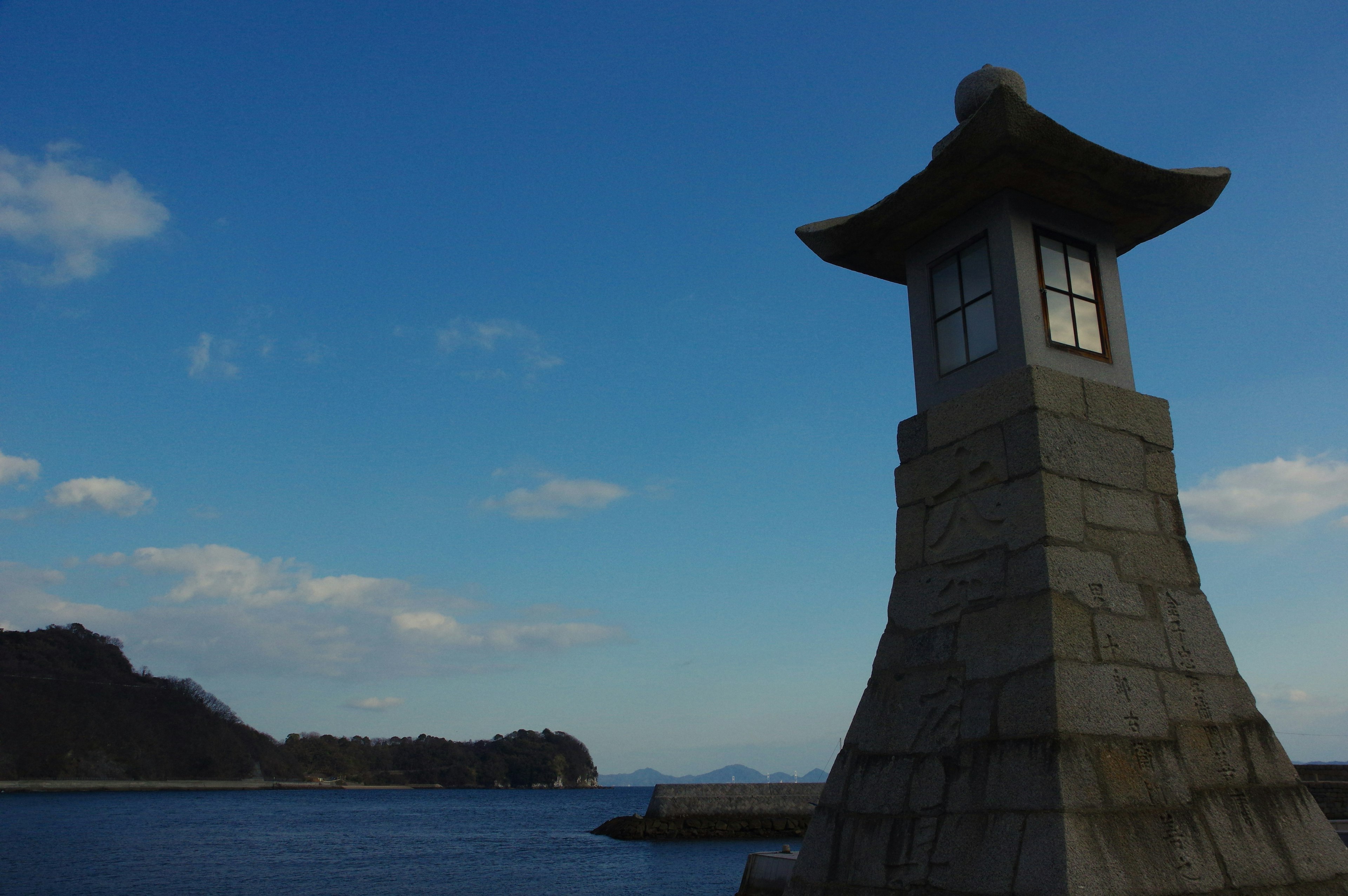 Faro de piedra en la costa con cielo azul y nubes