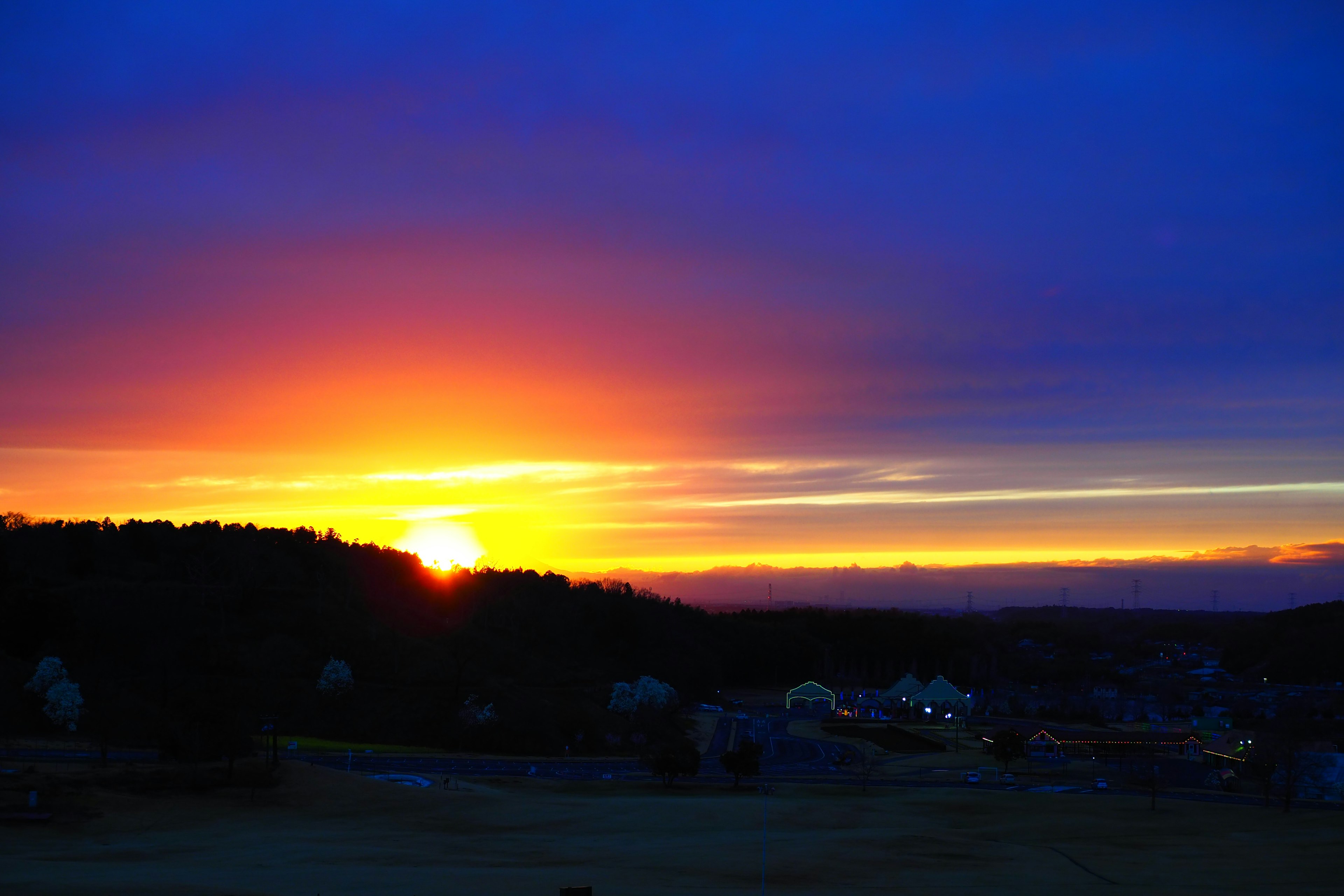 Schöne Sonnenuntergangslandschaft mit orangefarbenem und blauem Himmel, der Hügel umreißt