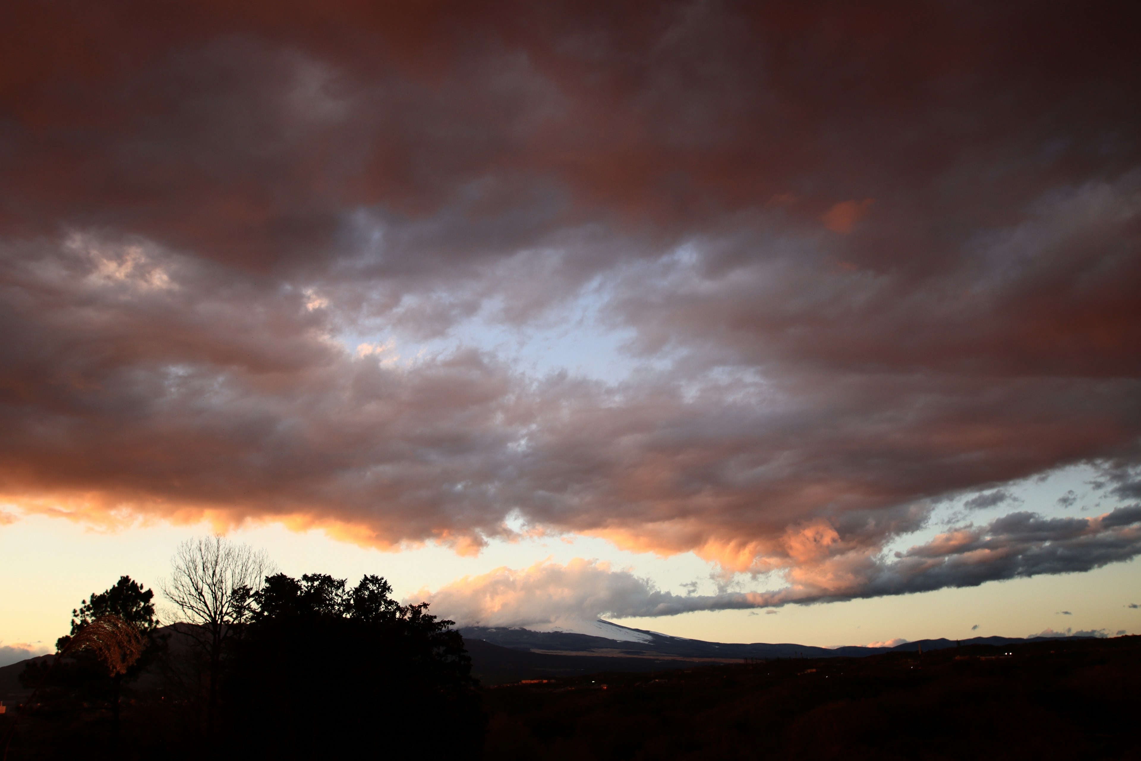 Cielo de atardecer dramático con nubes oscuras y silueta de montaña