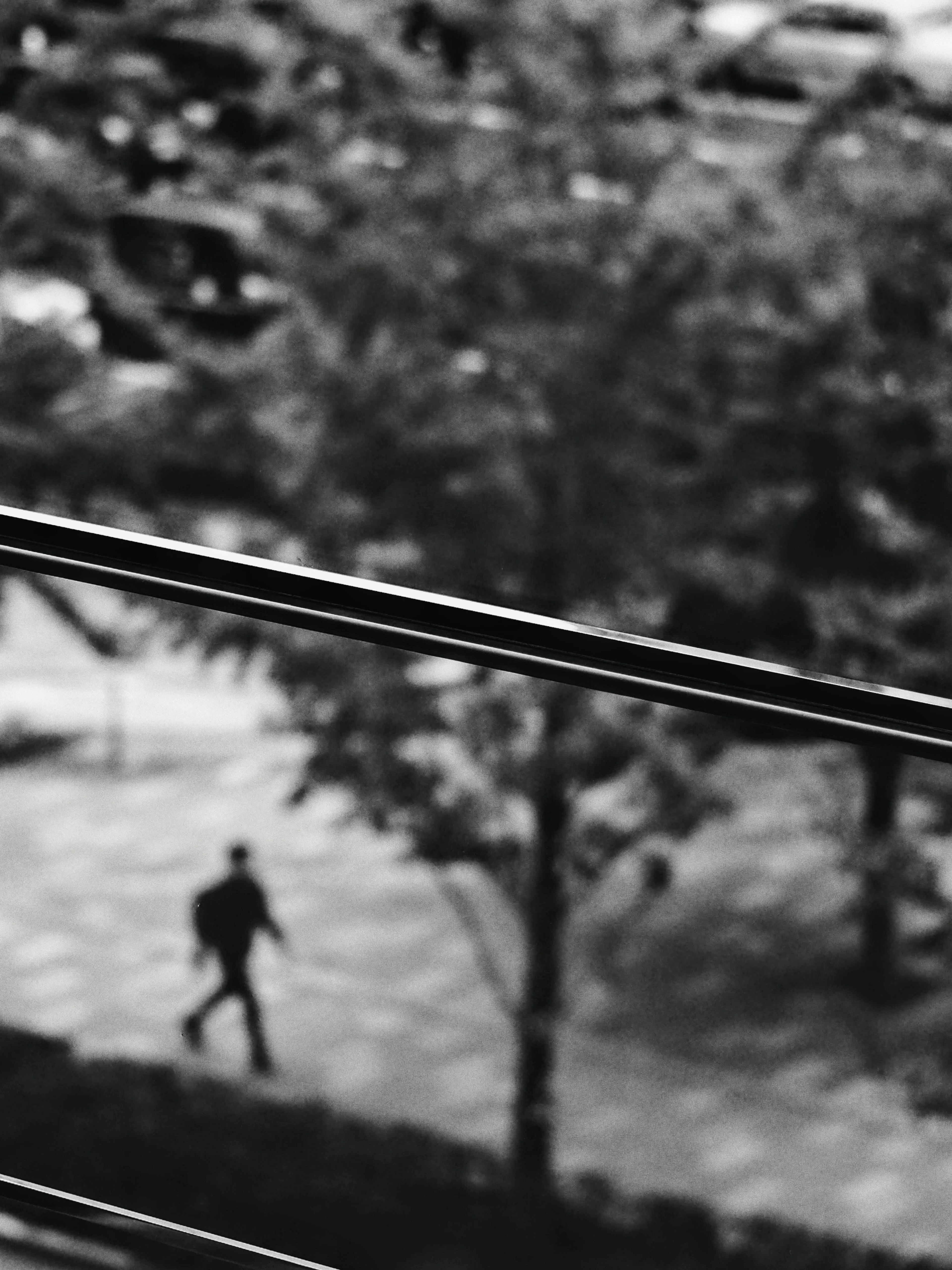 Silhouette d'une personne marchant dans une scène urbaine floue avec des arbres et des voitures