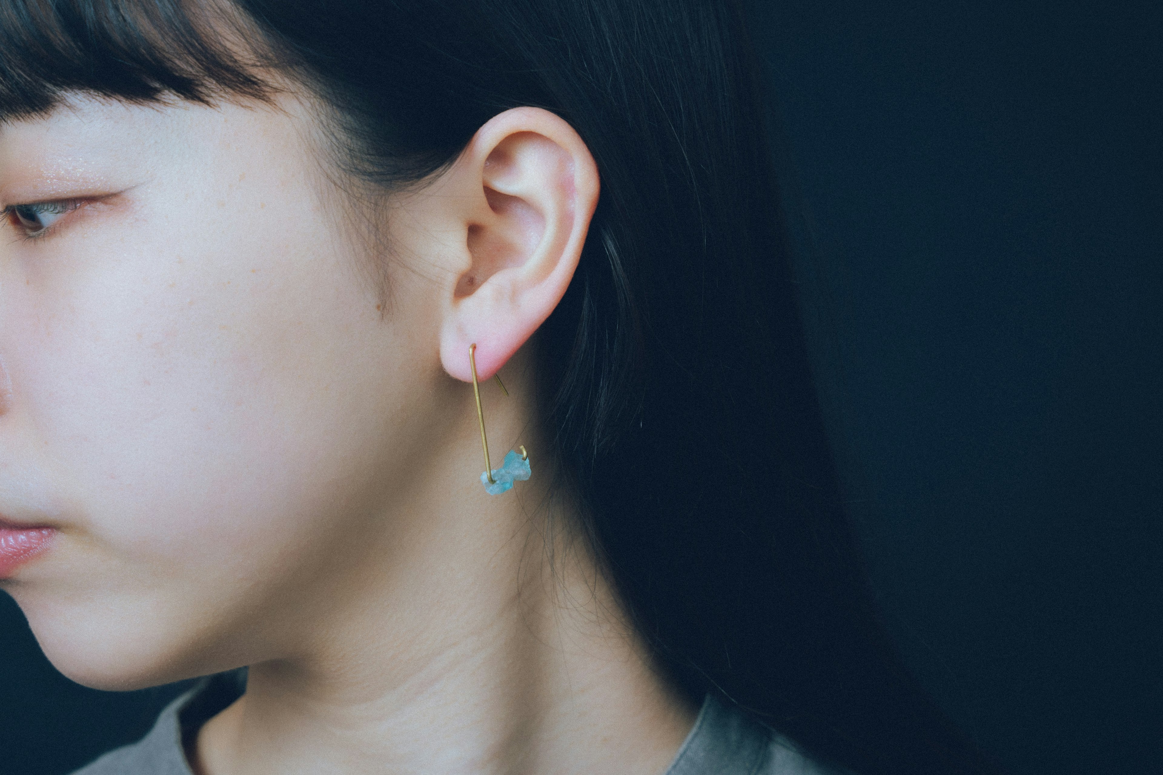 Profilo laterale di una donna con un orecchino blu