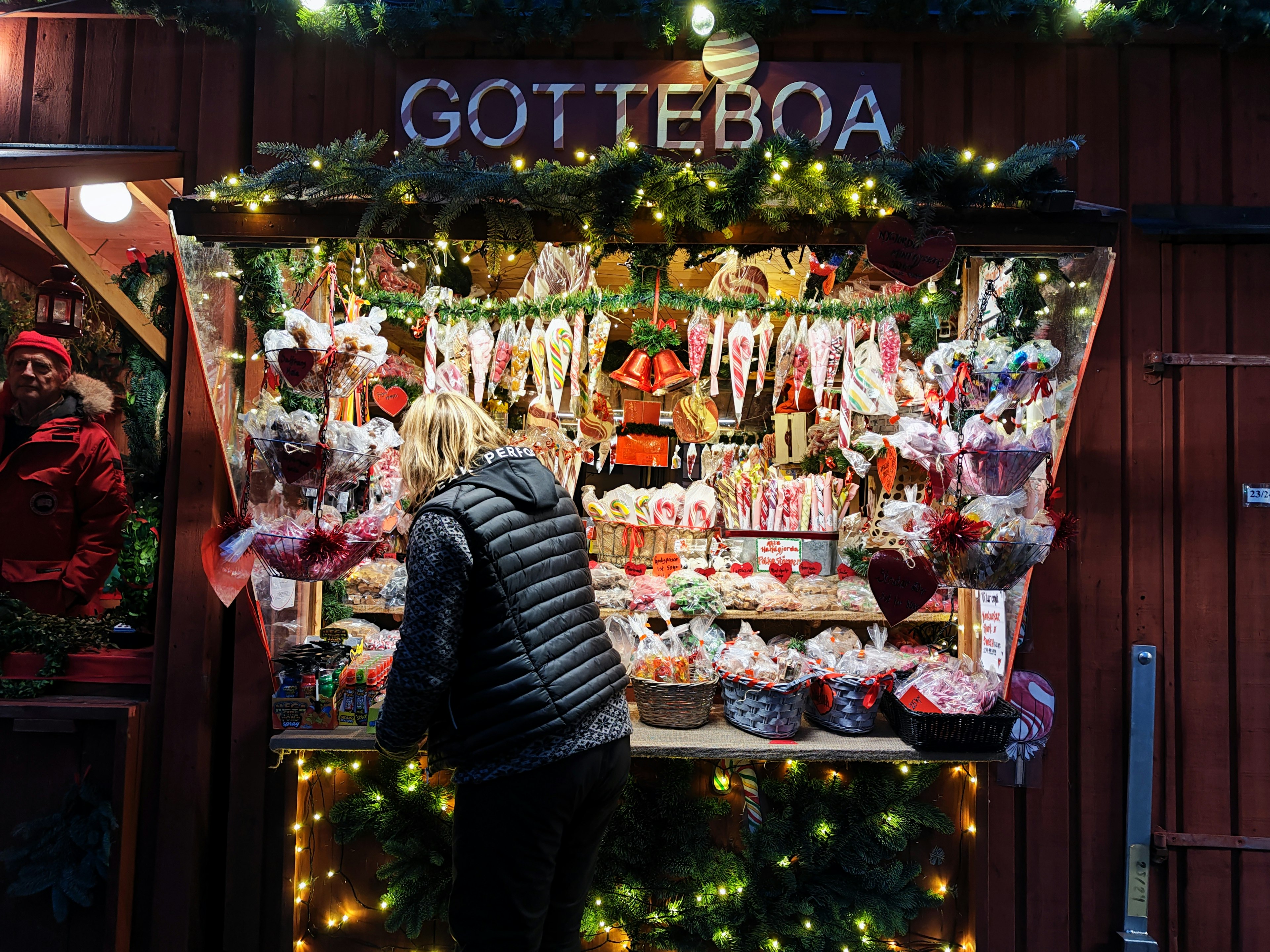 A person shopping at a colorful candy stall in a Christmas market