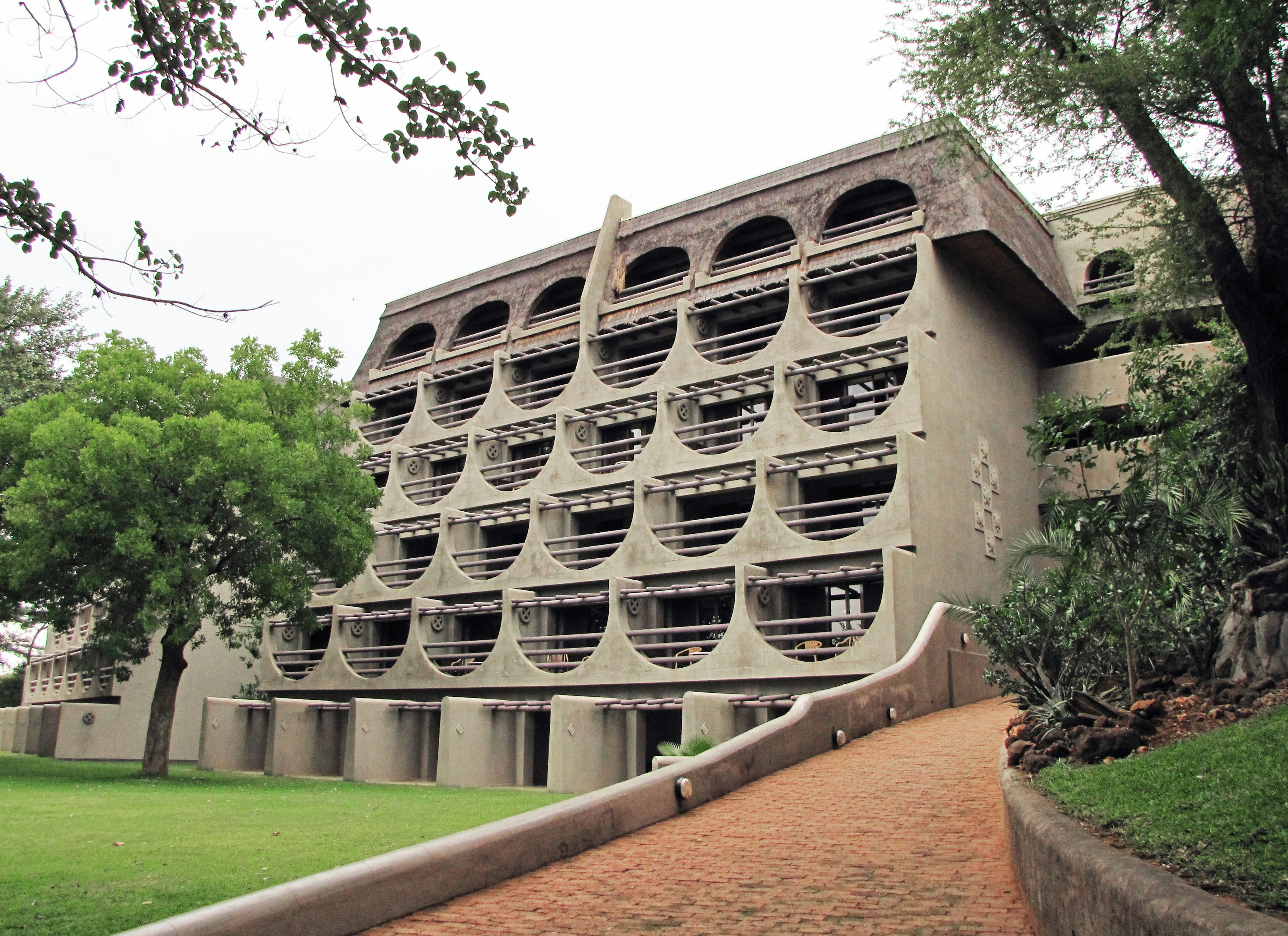 Unique concrete building design with lush garden and paved pathway