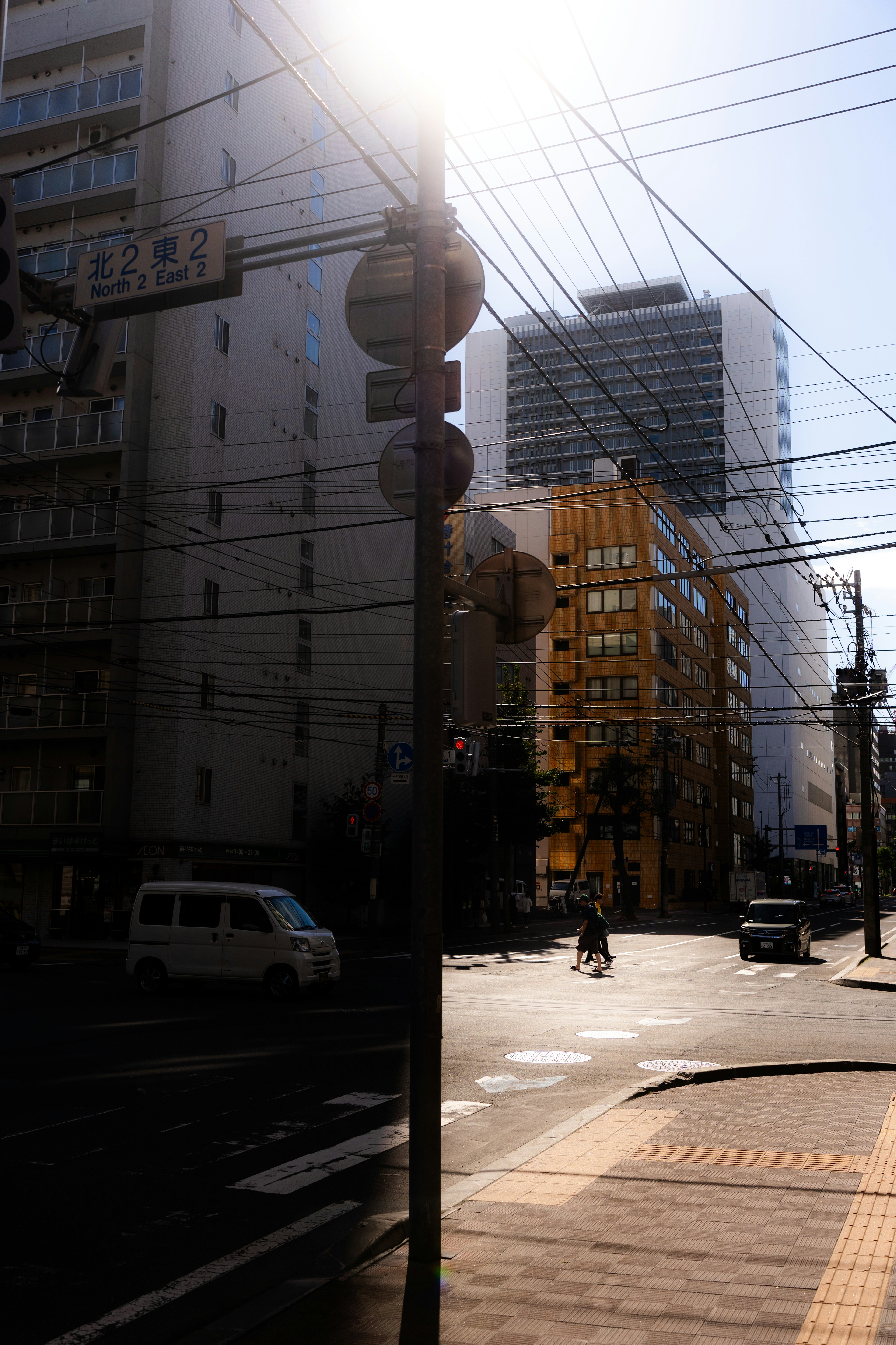 明るい日差しの中で交差点に立つ標識とビルが見える風景