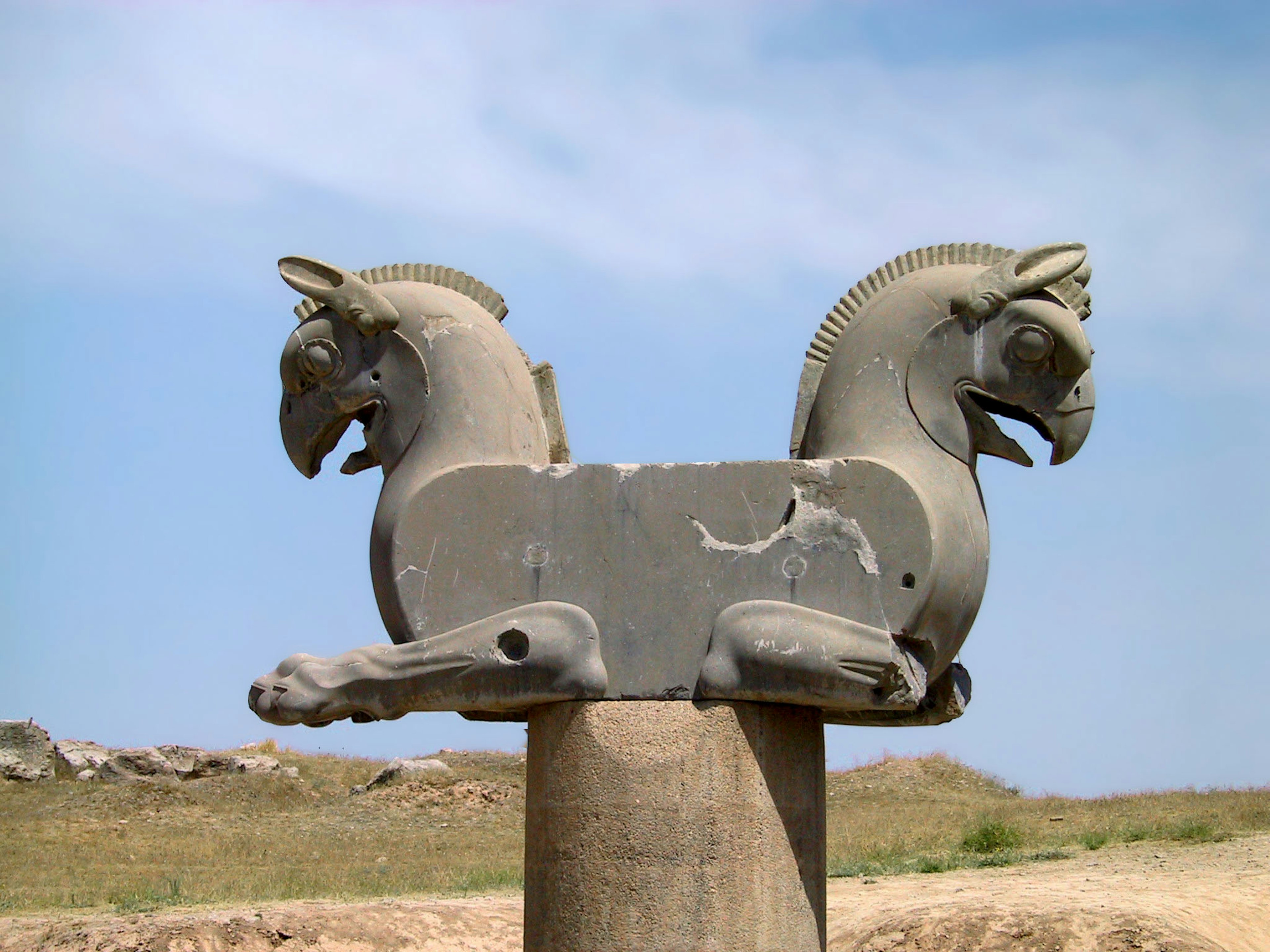 Eine Skulptur mit zwei Pferdeköpfen auf einem Pfeiler unter einem blauen Himmel