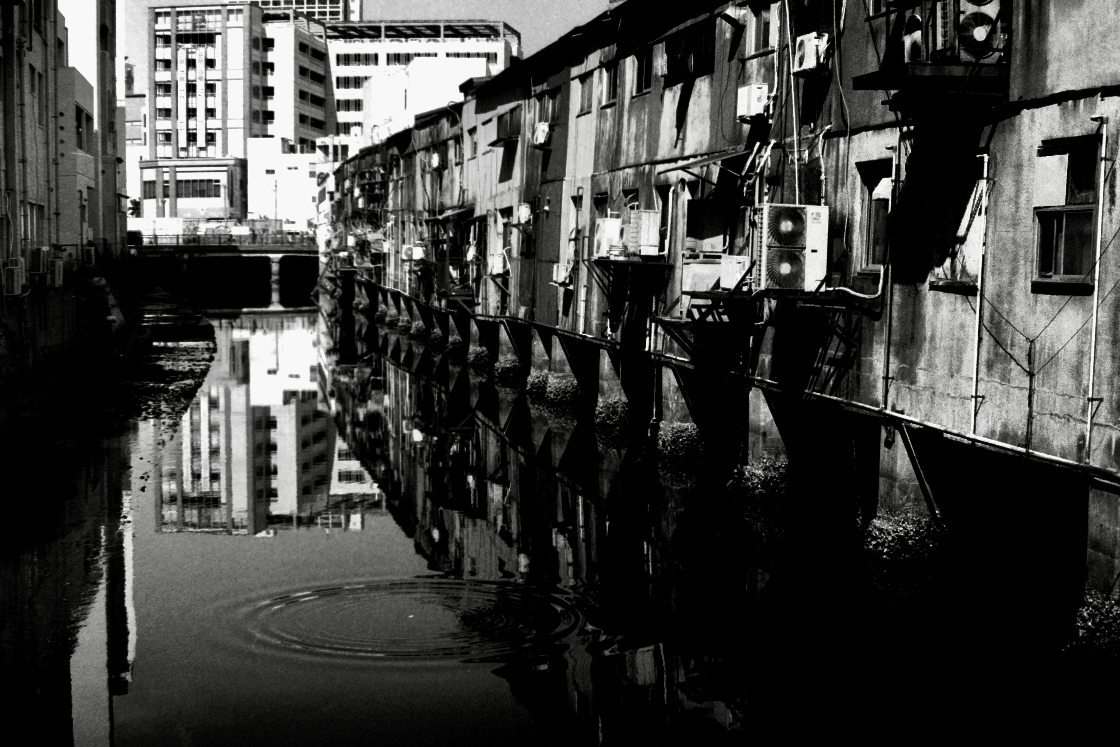 Foto hitam putih apartemen tua yang memantul di air