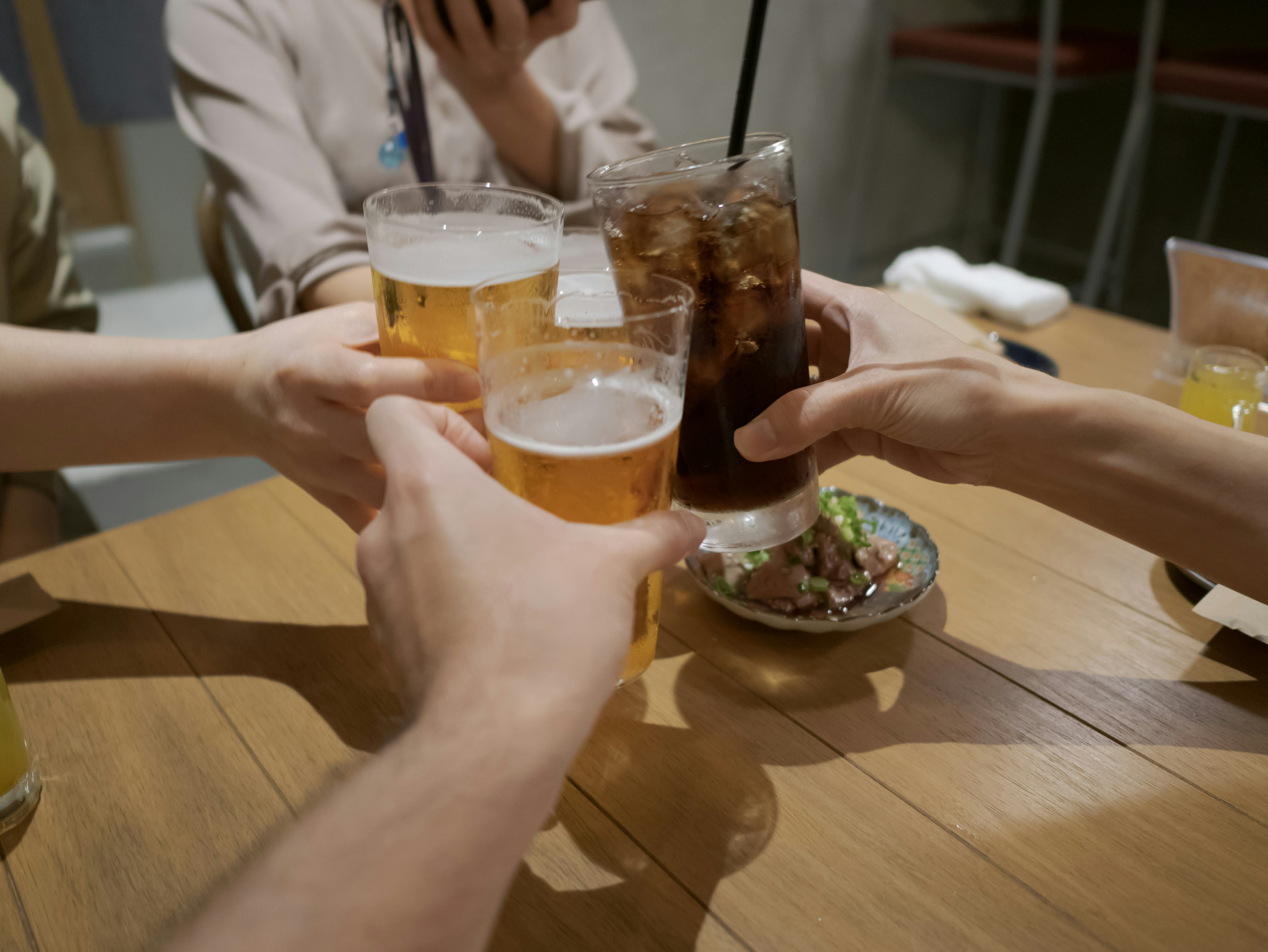 Mains levant des verres pour un toast avec des boissons sur une table en bois