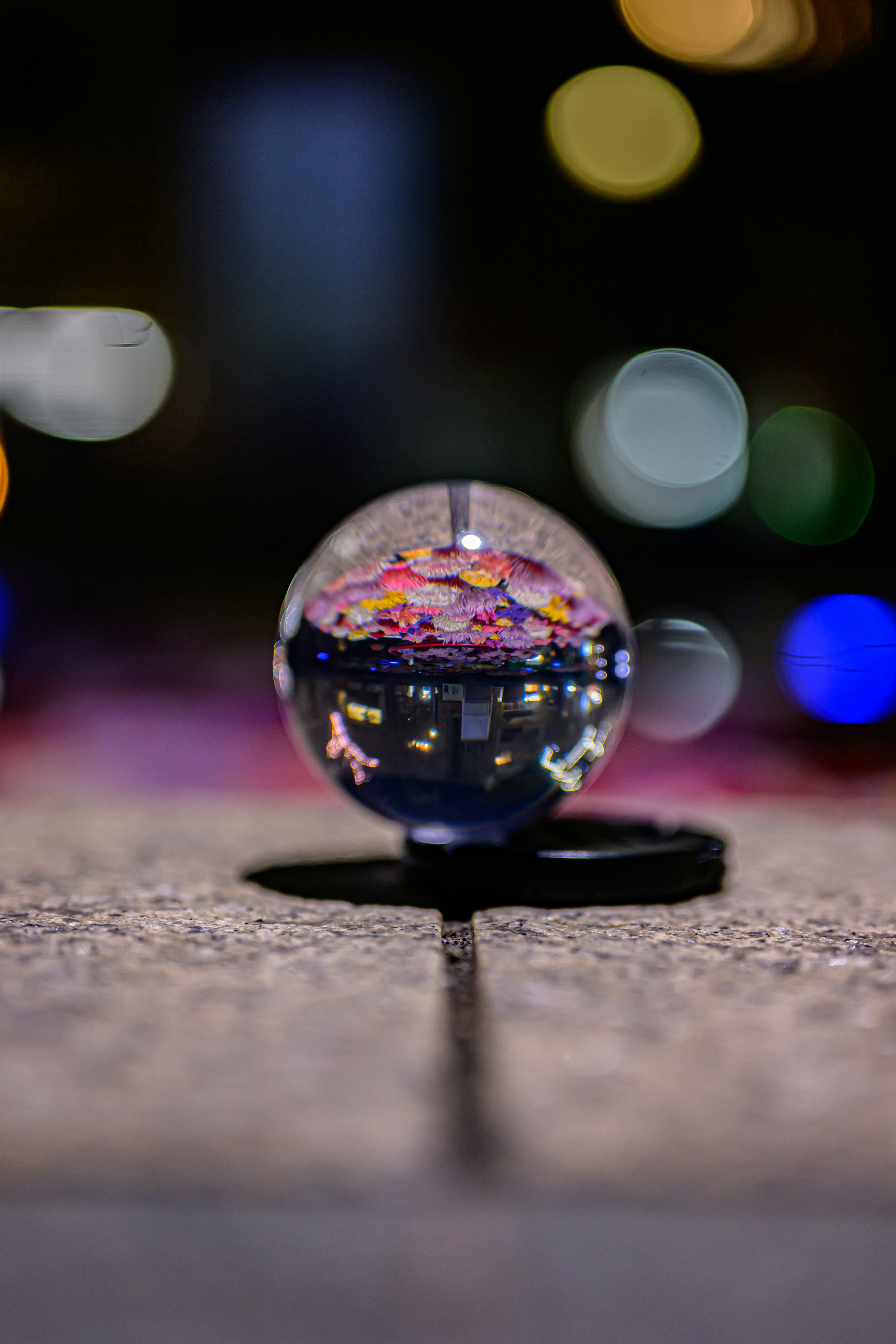 透明な球体の中に色とりどりの花の模様が映る夜の風景