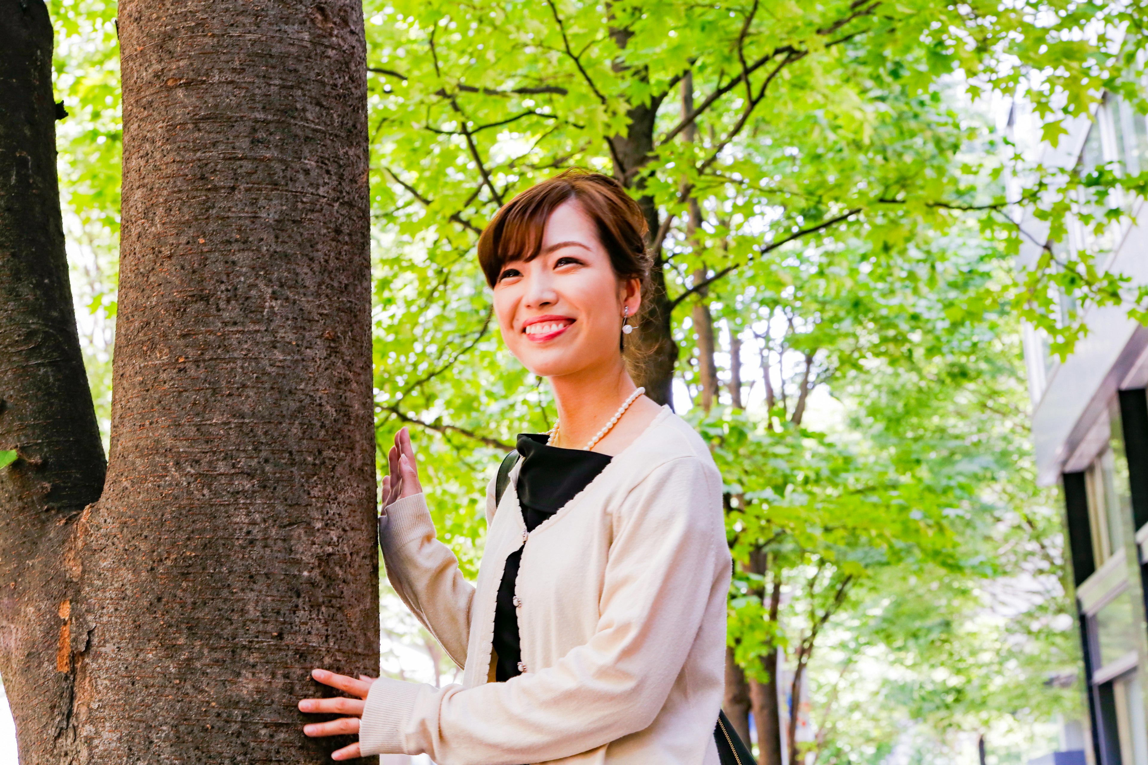 Mujer sonriente de pie cerca de un árbol verde en un parque