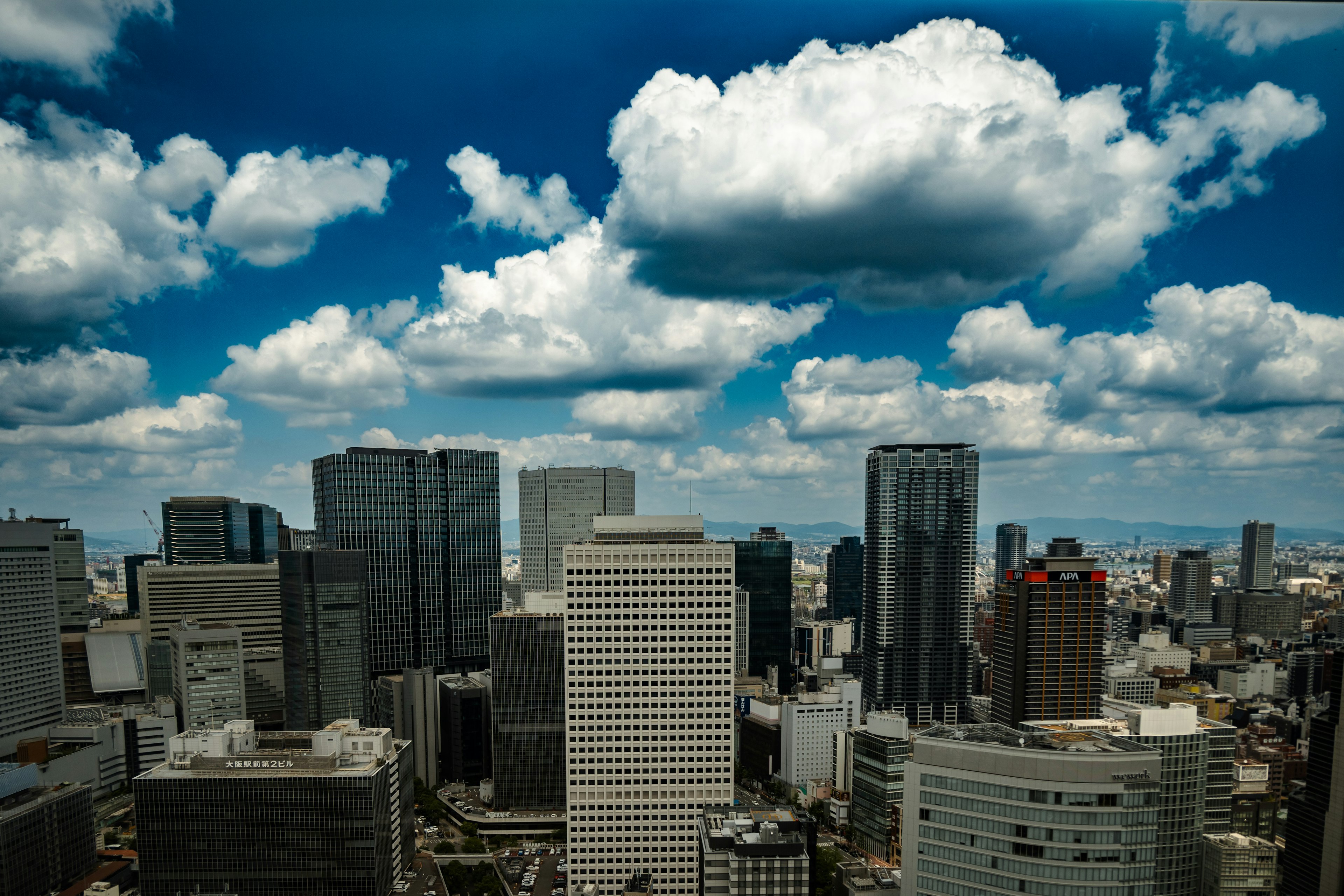 都市の高層ビル群と青空に浮かぶ白い雲の風景