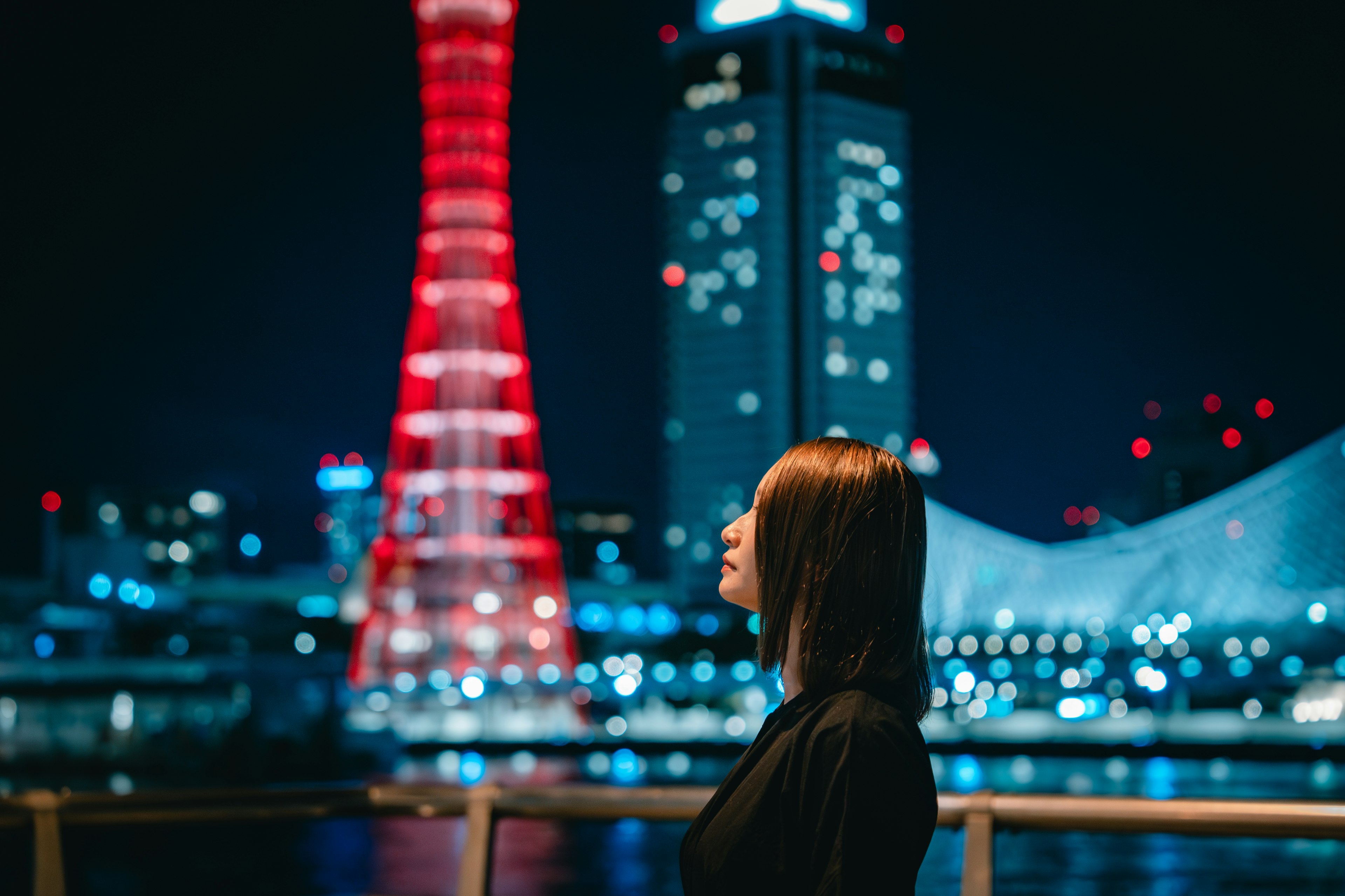 Perfil de una mujer contra un paisaje urbano nocturno con una torre roja