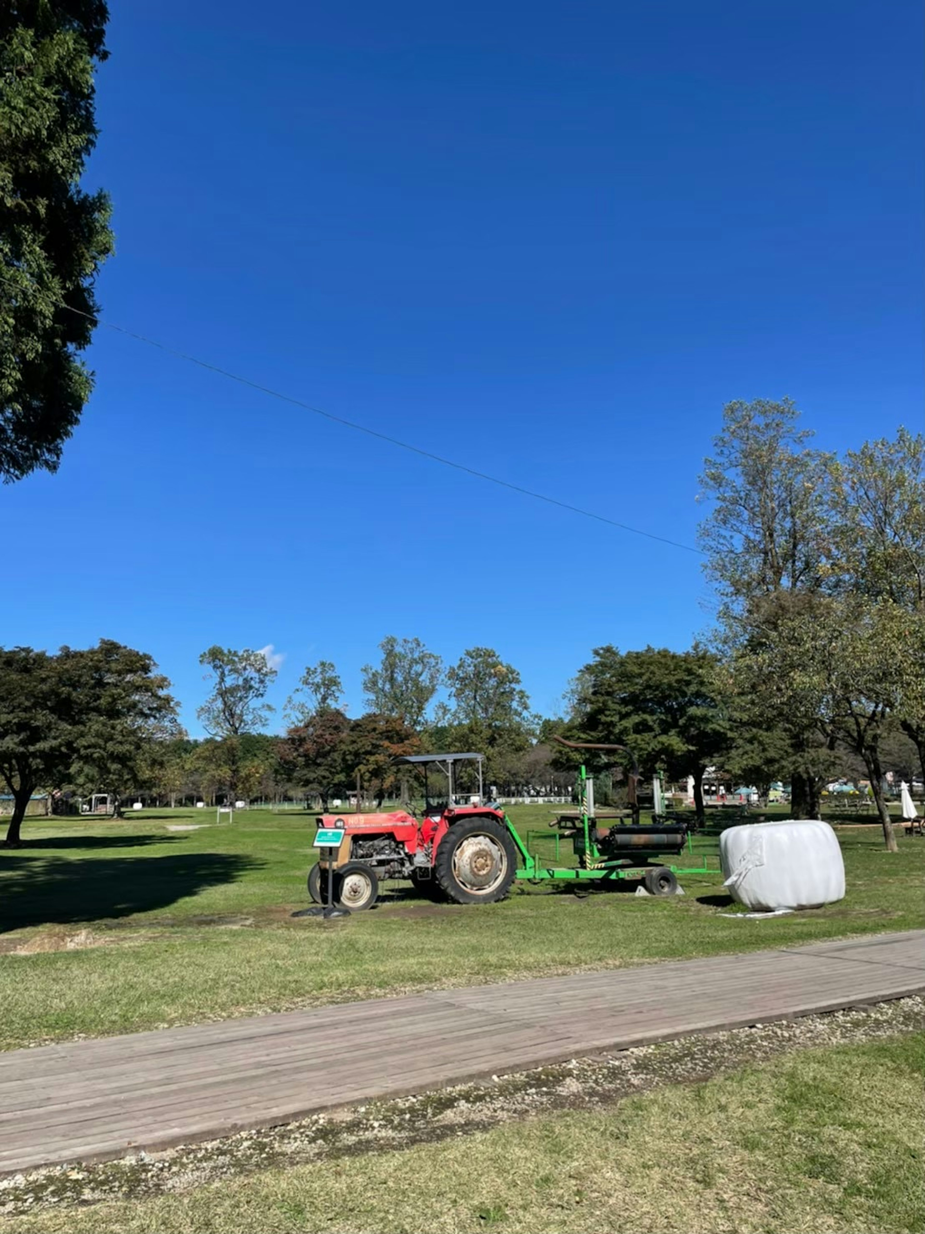 Park scene with a green tractor and a white bale under a clear blue sky