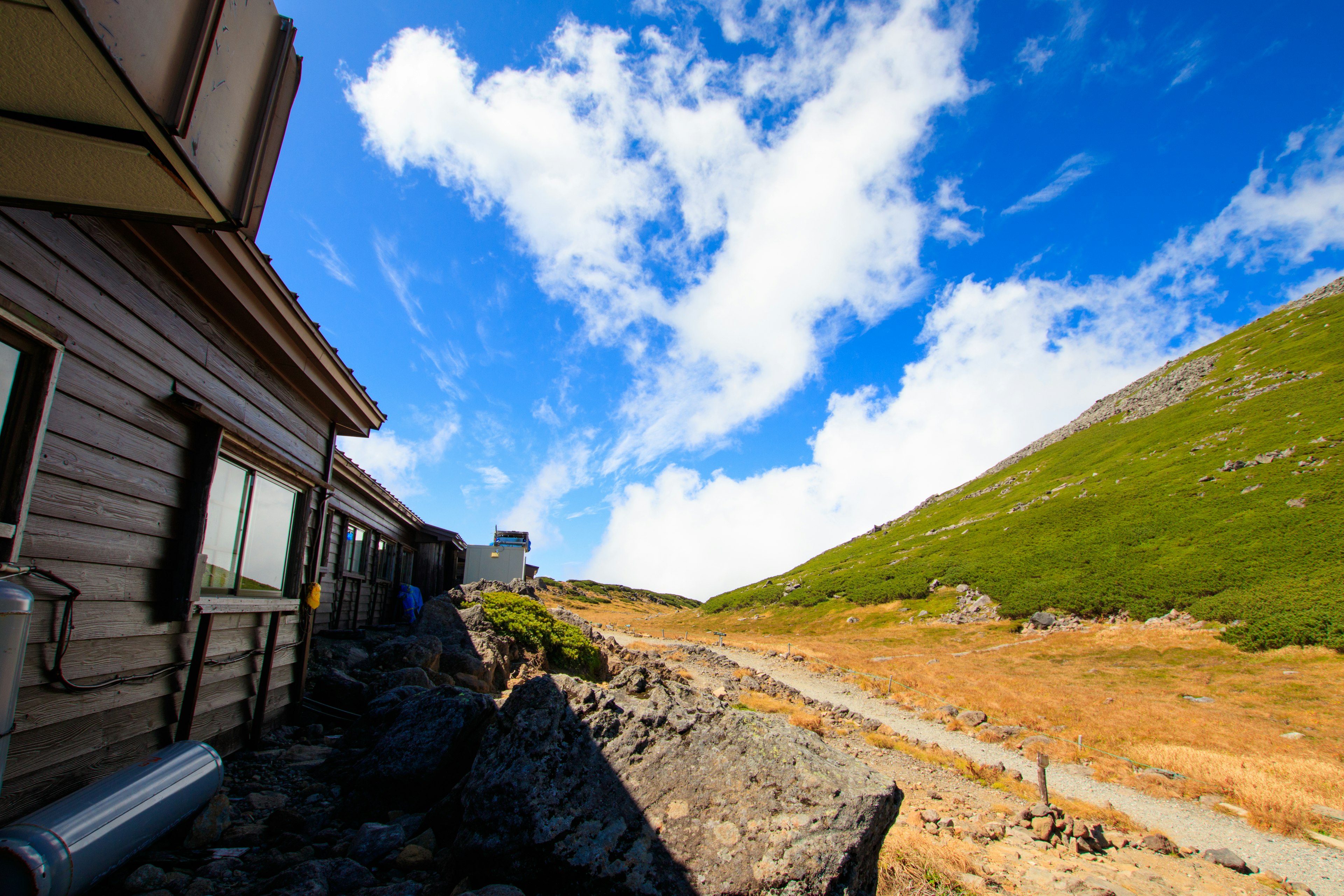 Malersicher Blick auf eine Hütte an einem Berghang unter einem blauen Himmel