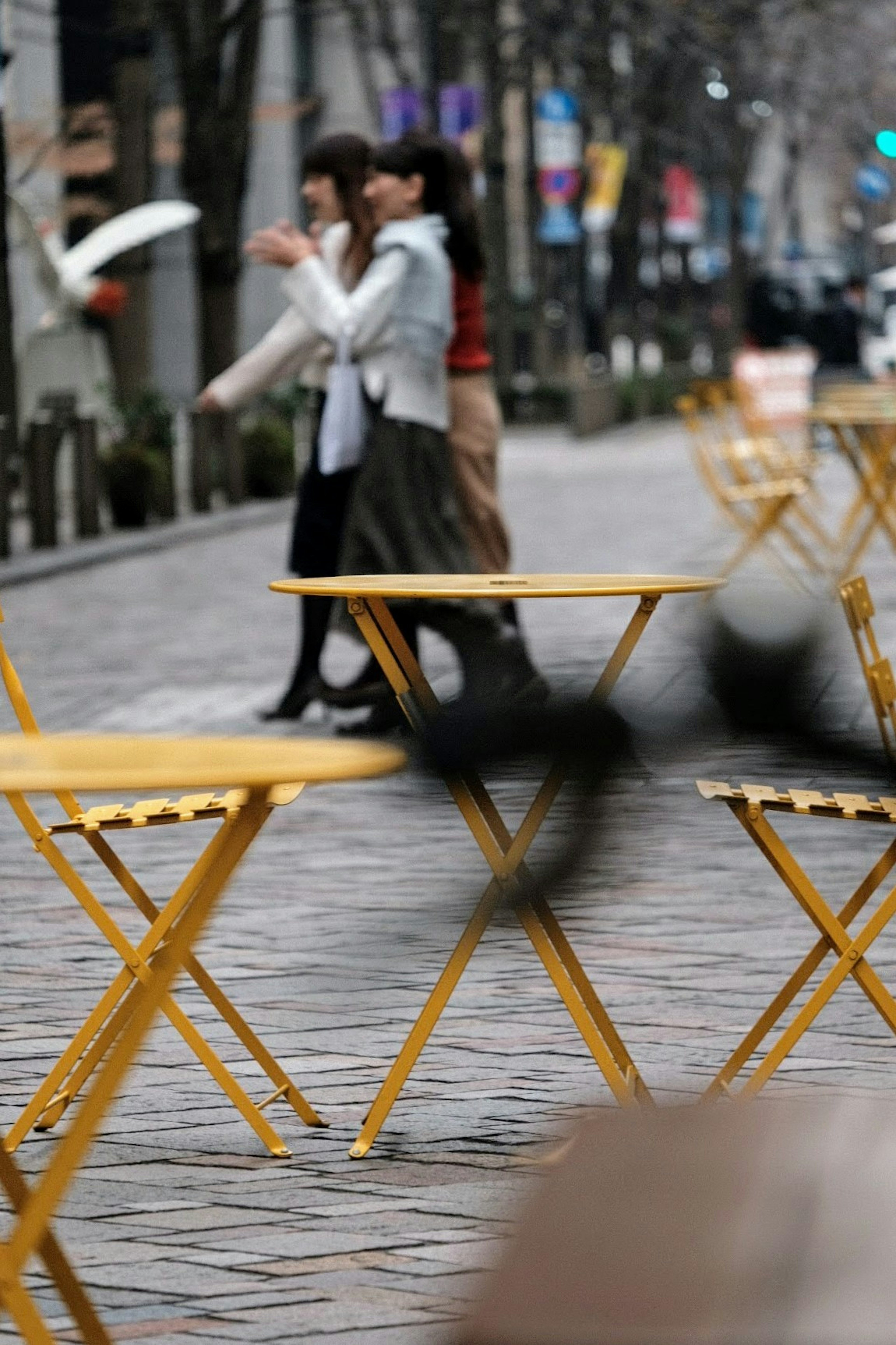 Frauen gehen in der Stadt mit gelben Tischen im Vordergrund