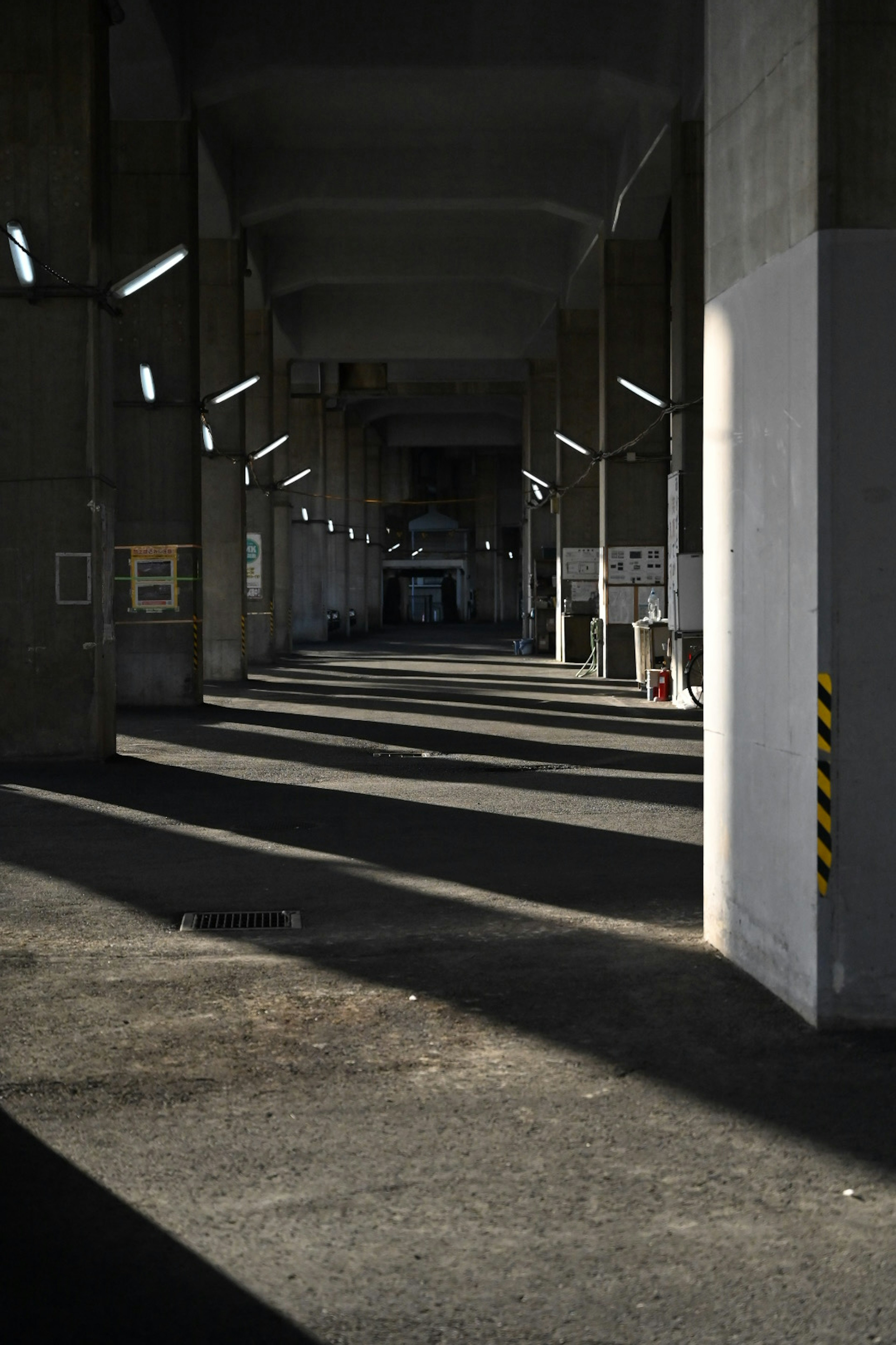 Lorong industri dengan bayangan panjang dan pencahayaan atap