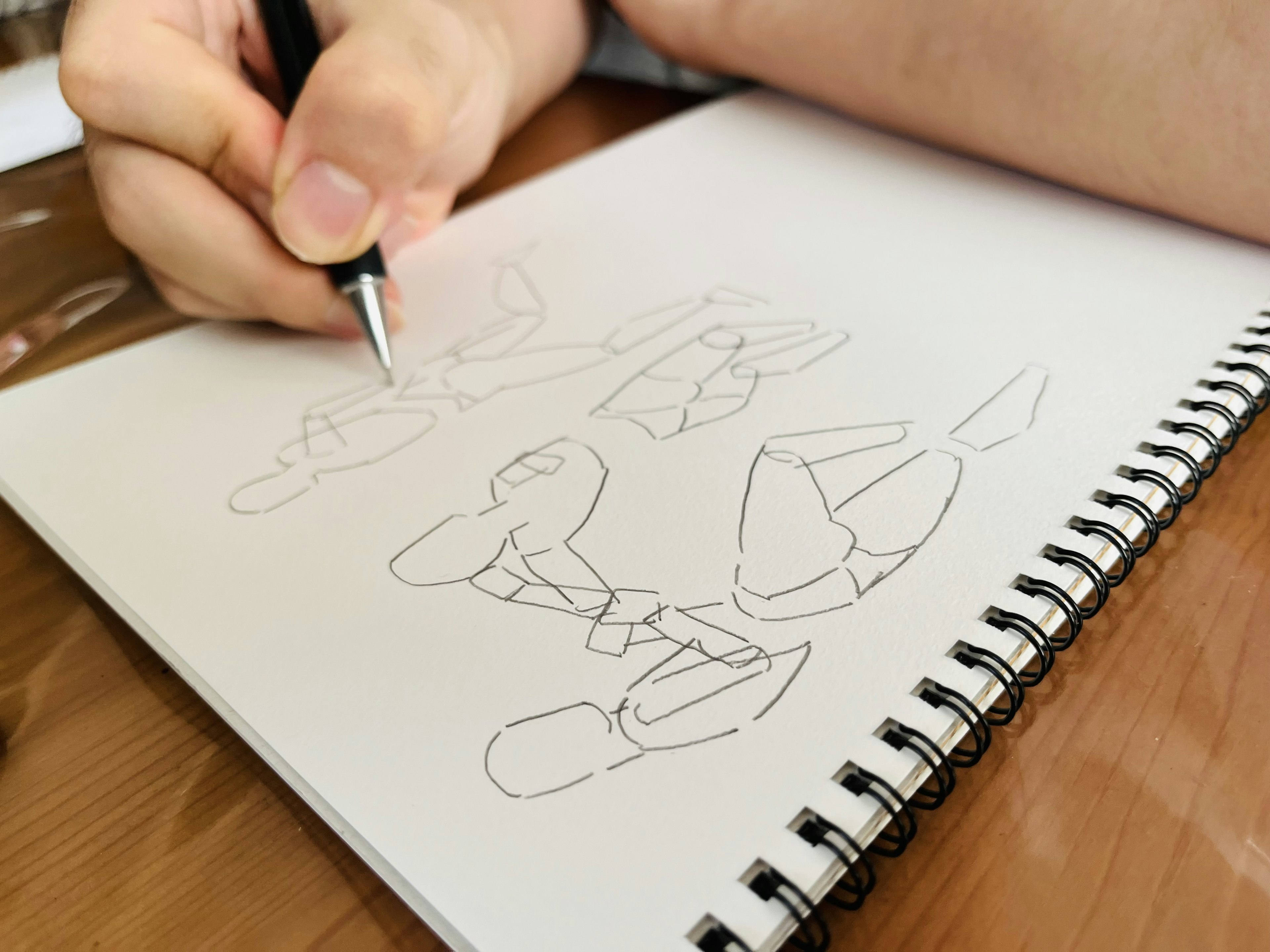 A person holding a pen sketching characters in a notebook