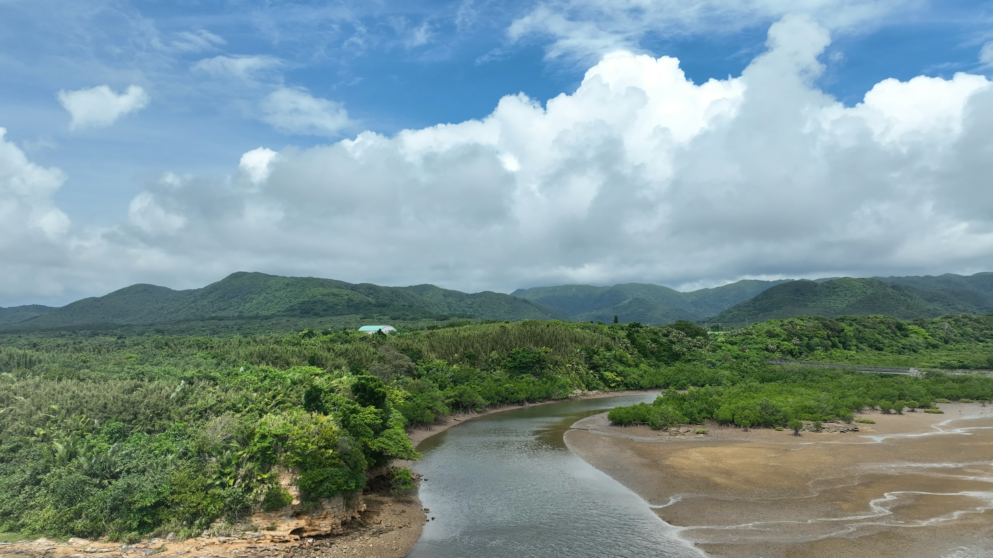 Paisaje de montañas verdes y cielo azul con un río que fluye en armonía con la naturaleza circundante