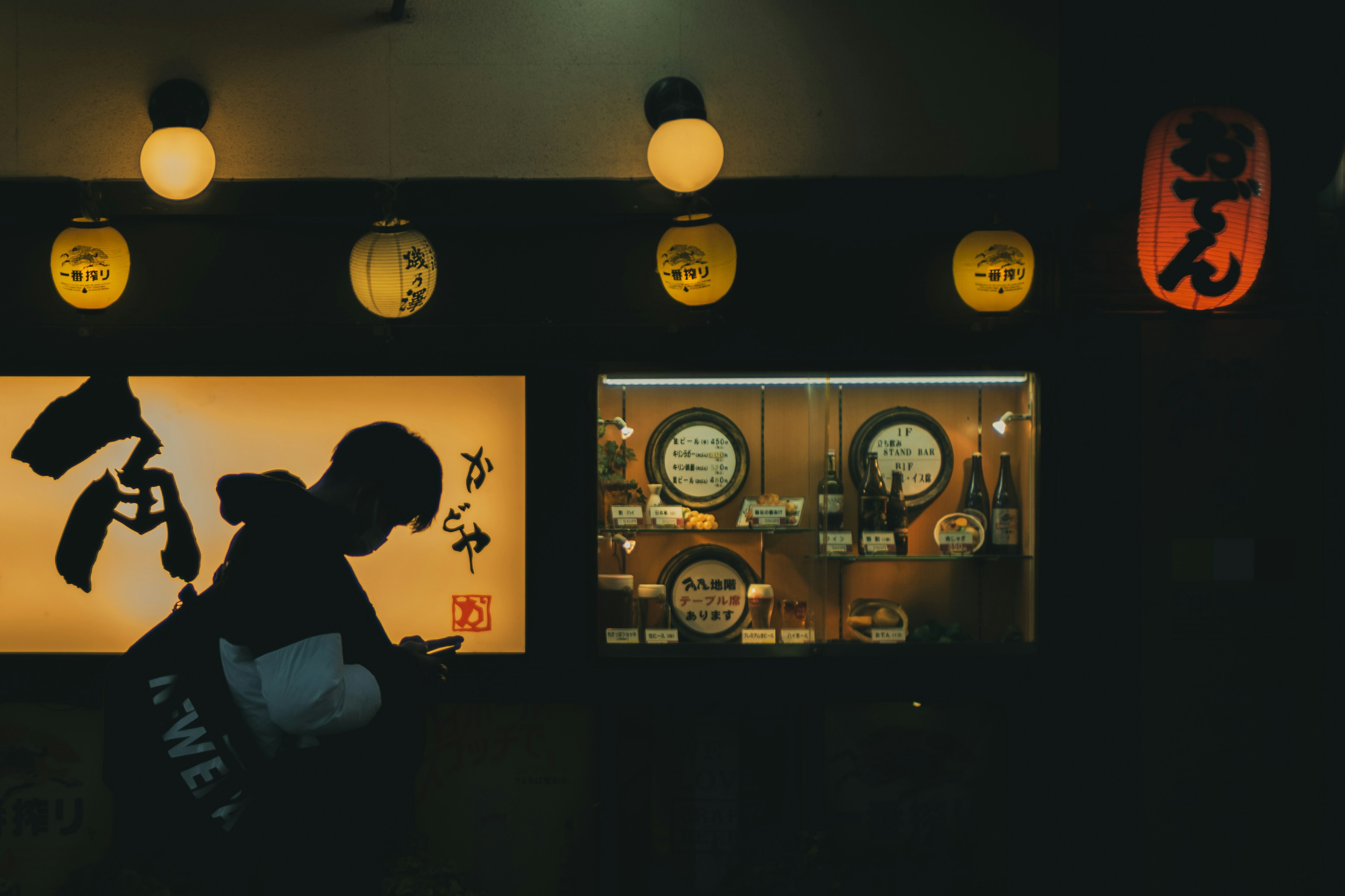 Silhouette d'une personne devant un izakaya japonais avec des lanternes