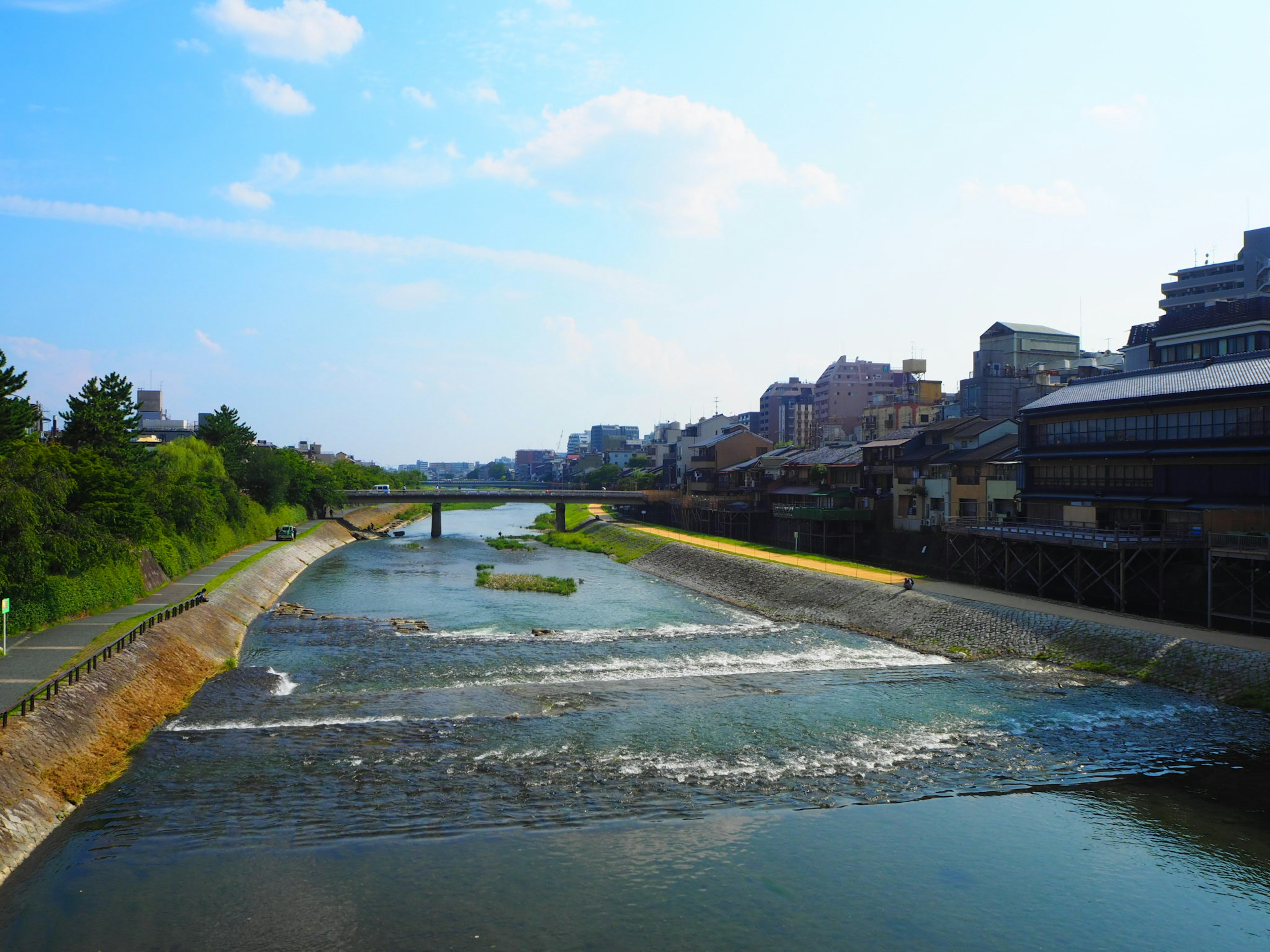 Malersicher Blick auf einen ruhigen Fluss, der durch eine Stadt unter einem blauen Himmel fließt