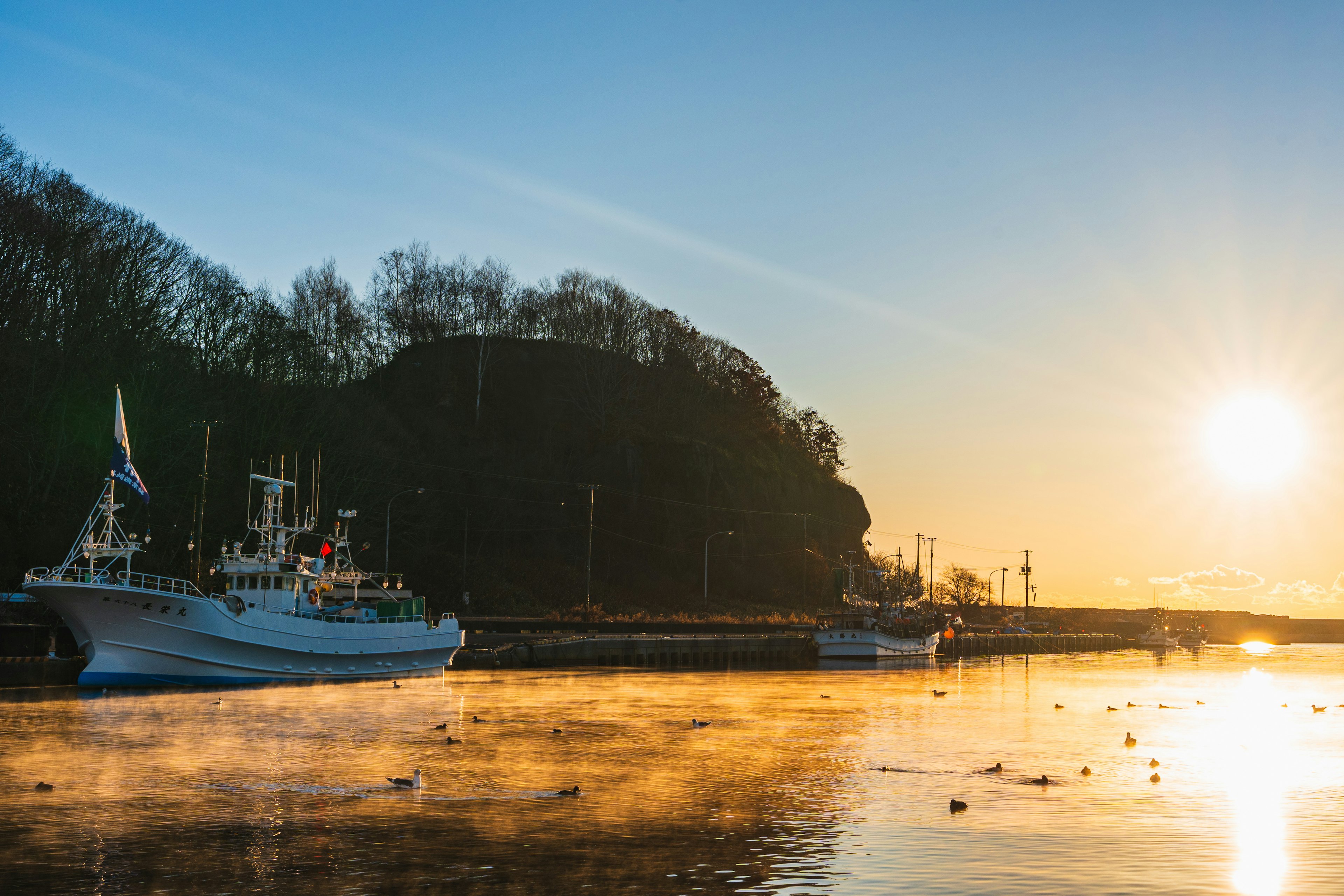 A serene harbor scene with boats illuminated by sunrise