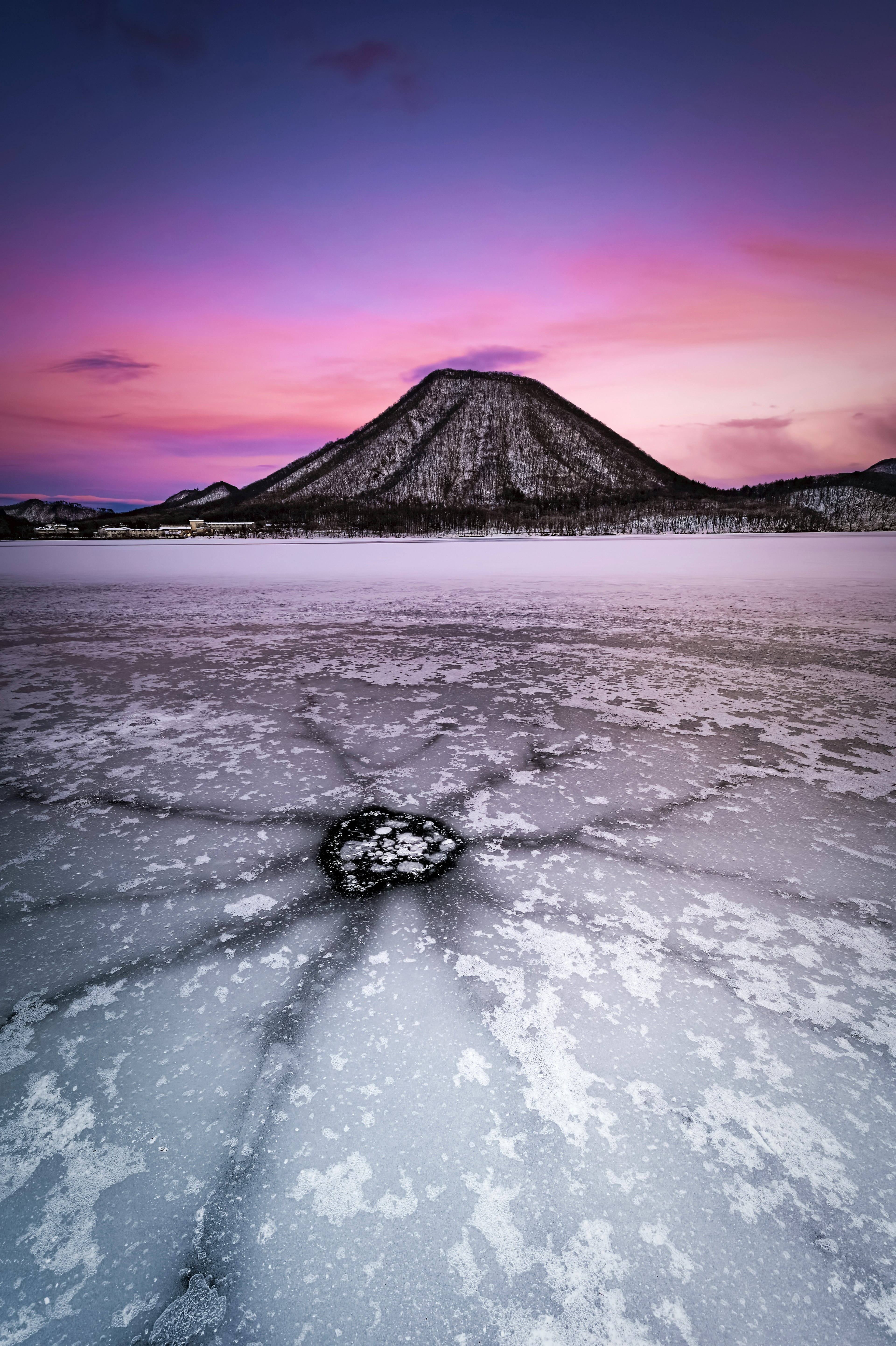 雪に覆われた山と氷の湖の風景が美しい夕焼けに照らされている