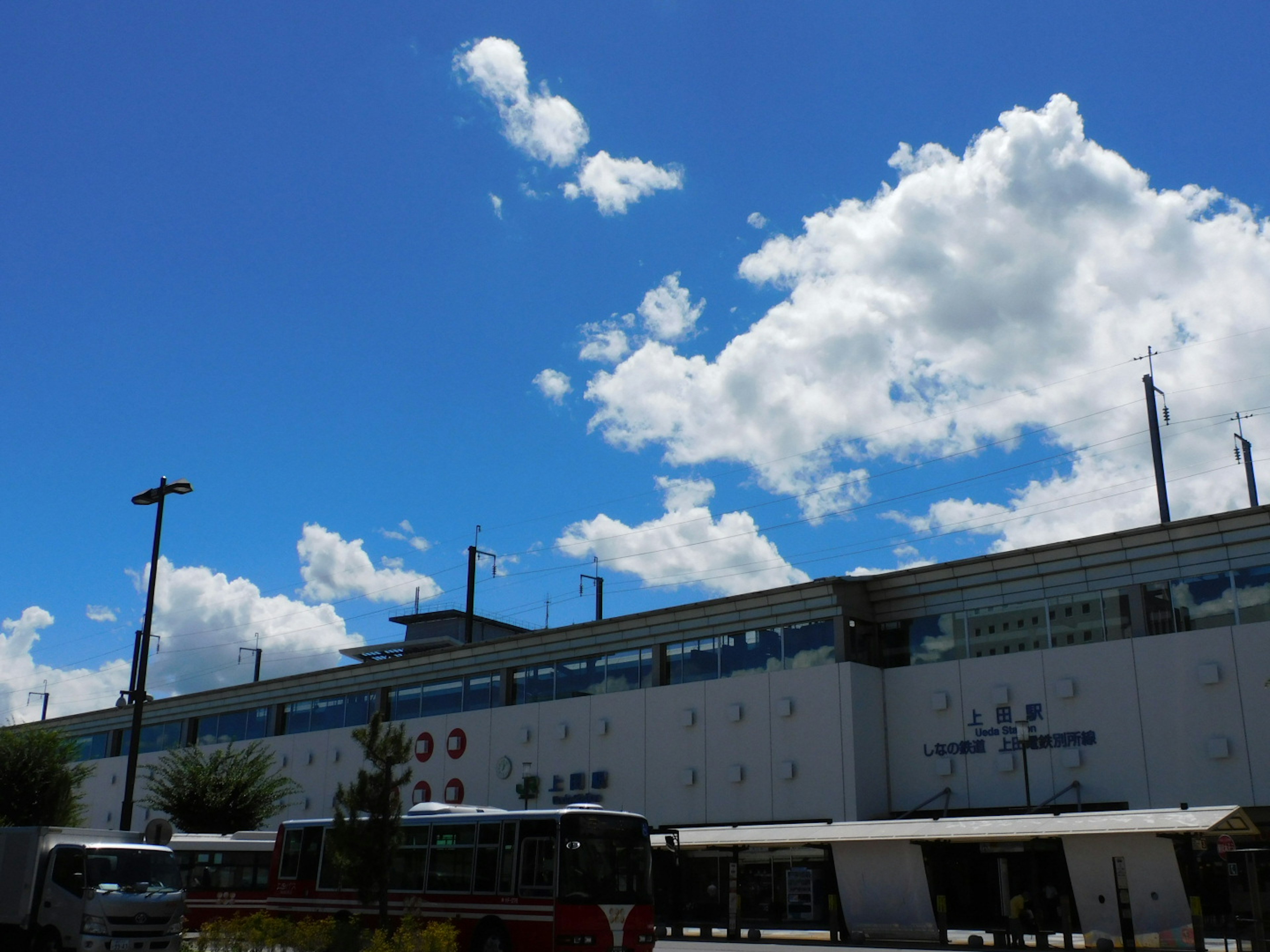 Bangunan stasiun di bawah langit biru cerah dengan awan berbulu