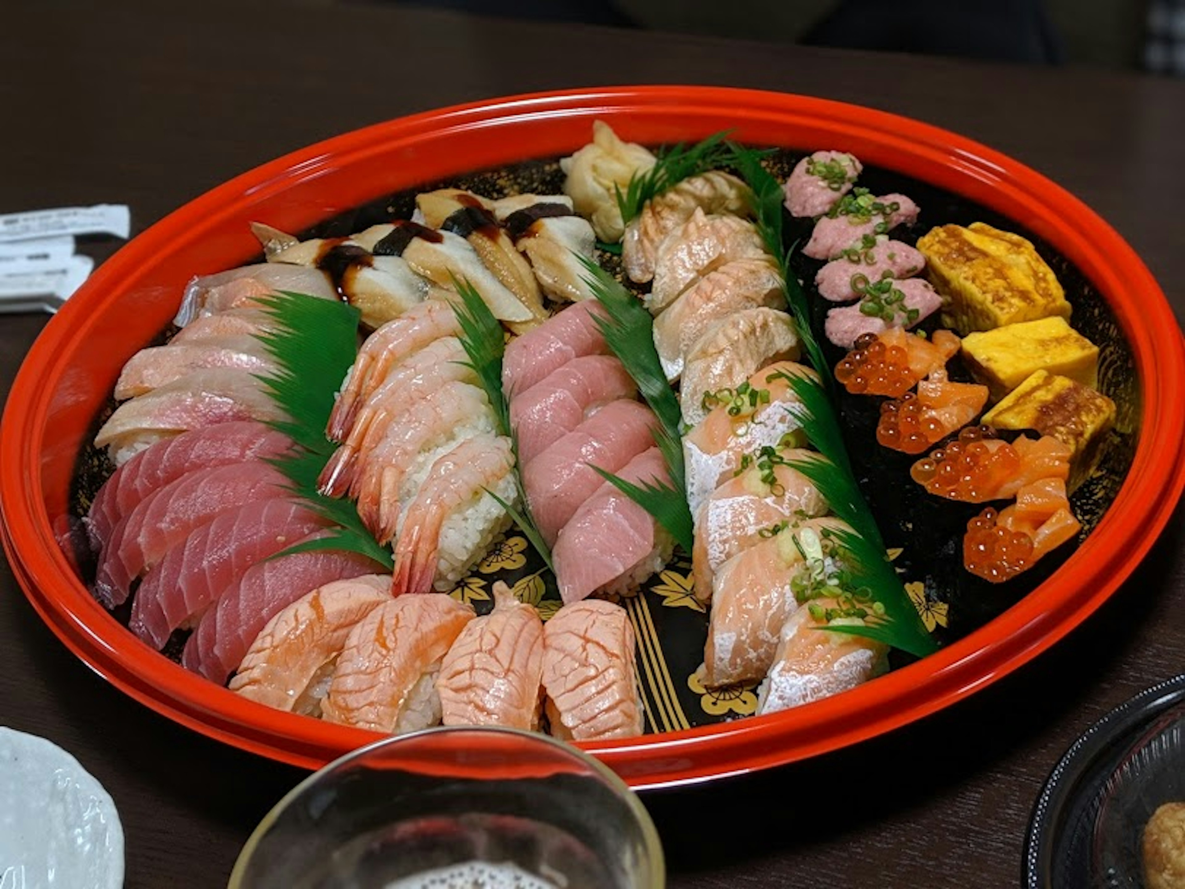 Assorted sushi displayed on a red platter with various toppings