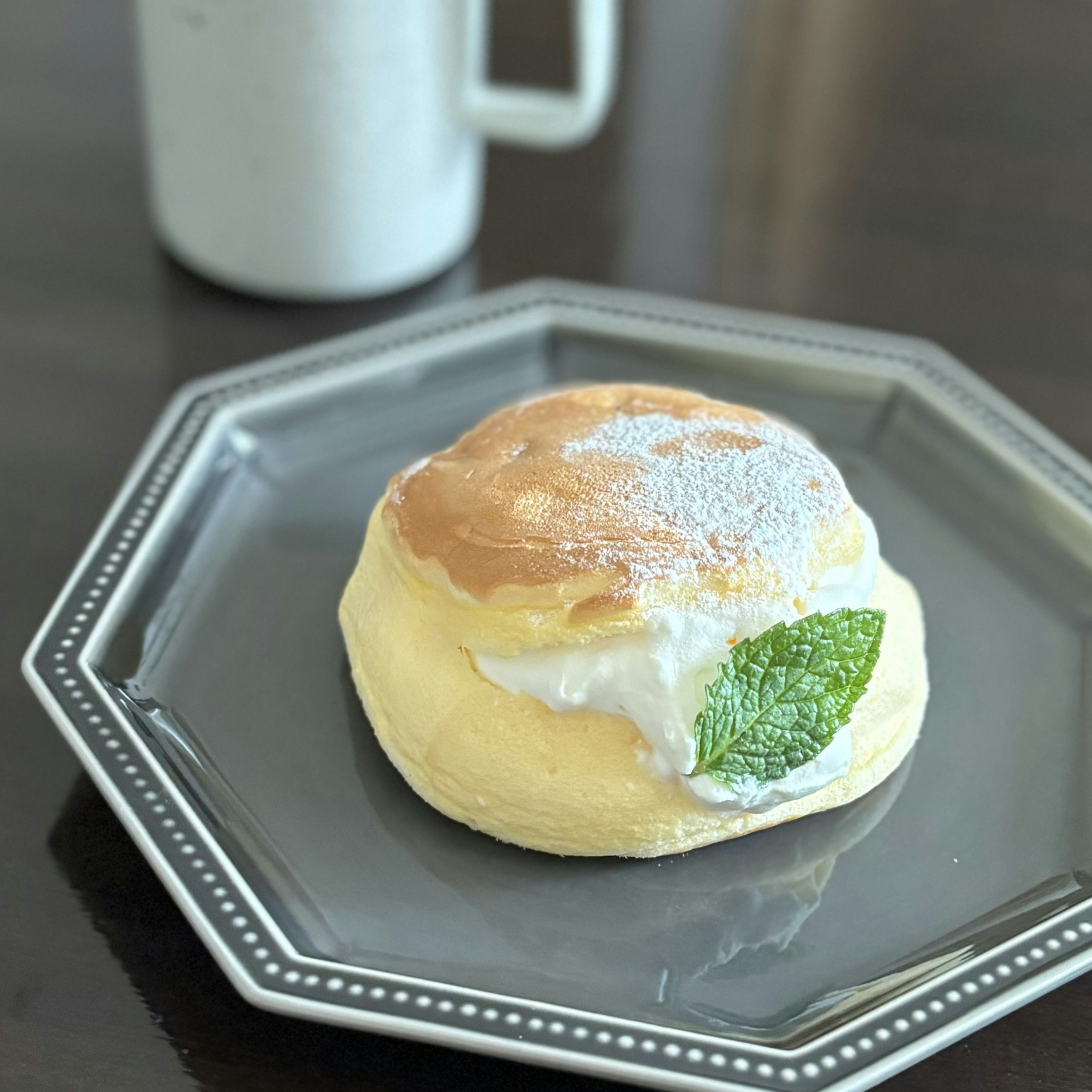 ふわふわのパンケーキにクリームとミントの葉がトッピングされたデザート