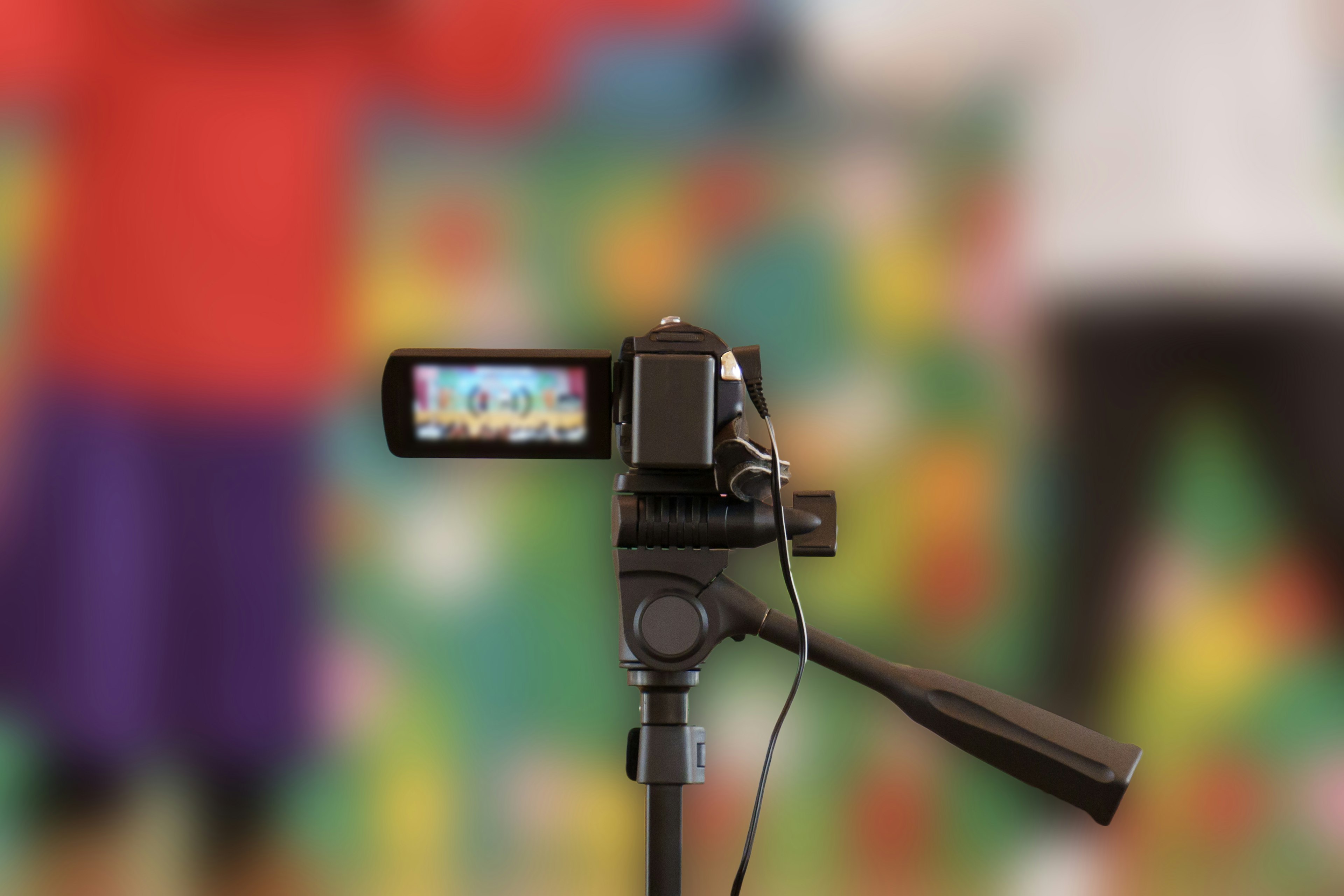 Video camera on a tripod with a colorful background