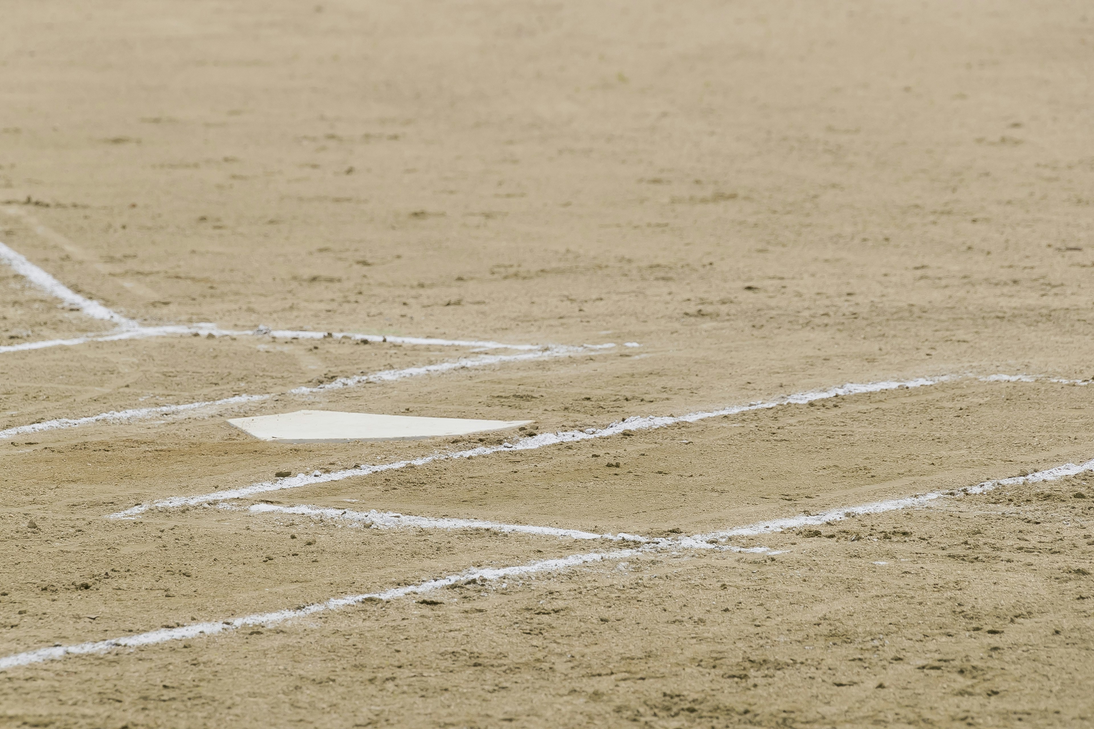 Parte di un diamante di baseball visibile su un campo sabbioso con linee bianche e basi segnate