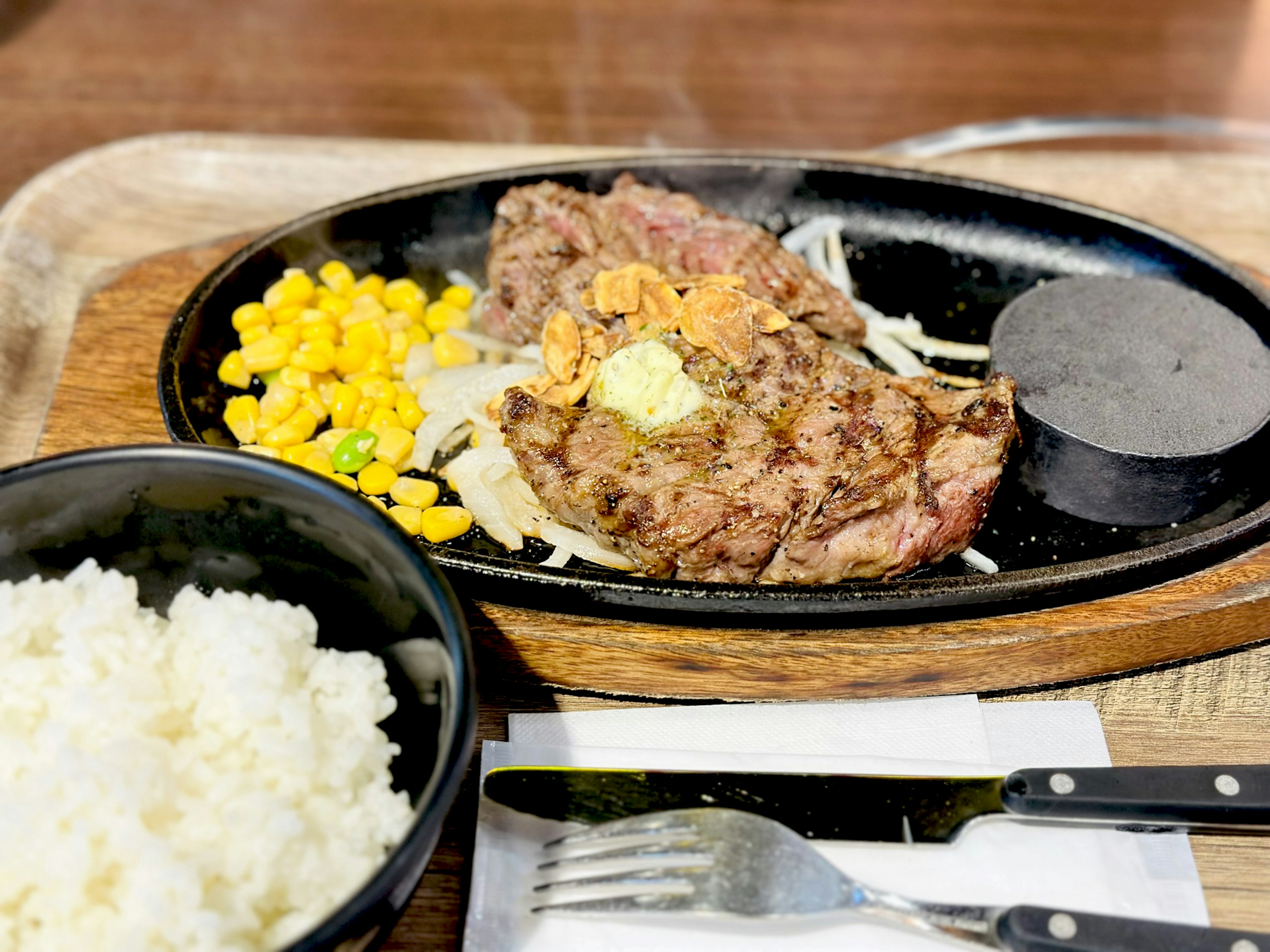 Sizzling steak served on a hot plate with corn and rice