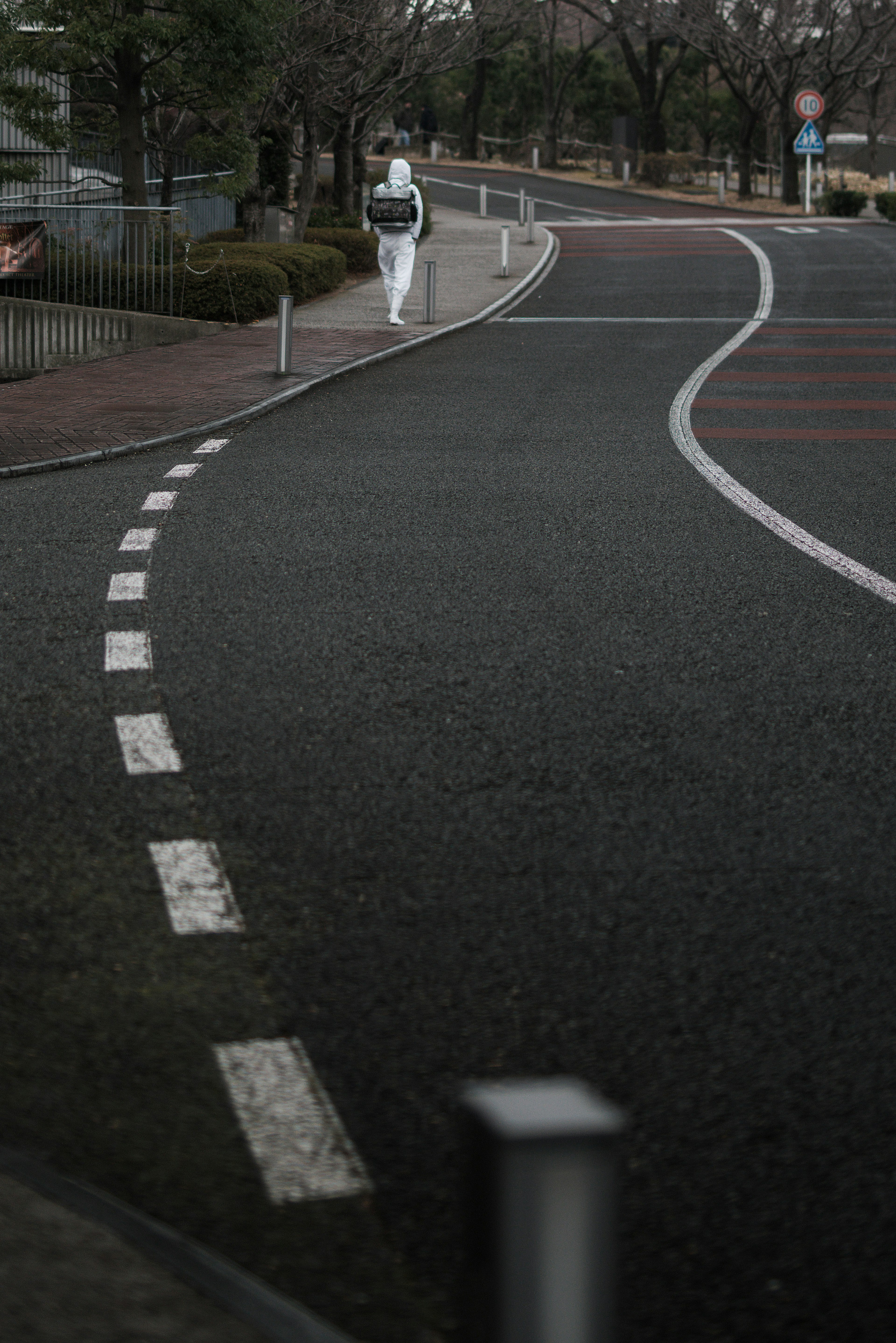 Une personne en tenue blanche marchant le long d'une route sinueuse