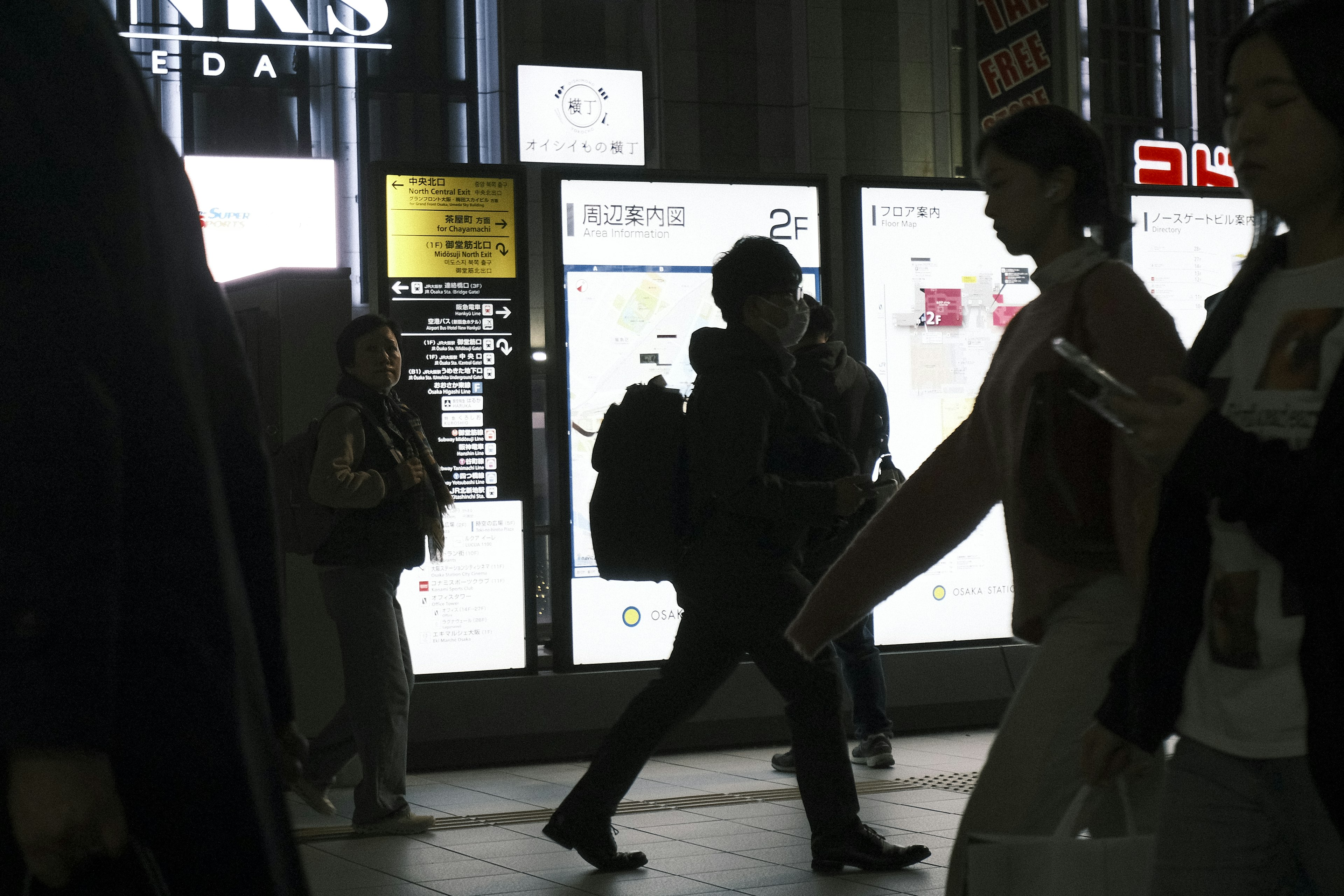 Scène urbaine sombre avec des gens marchant et des enseignes lumineuses