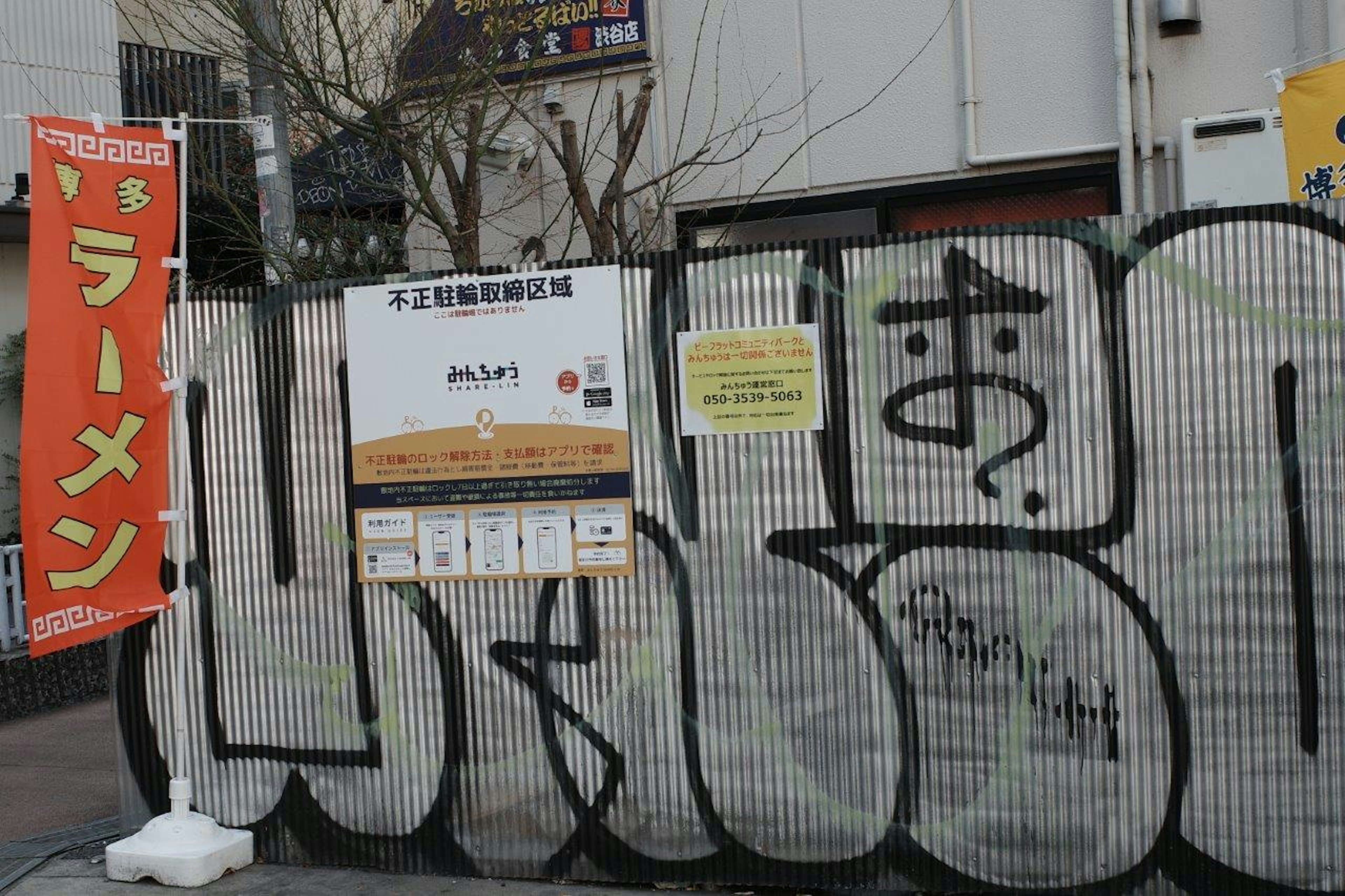 Scene of a ramen shop sign and graffiti-covered fence