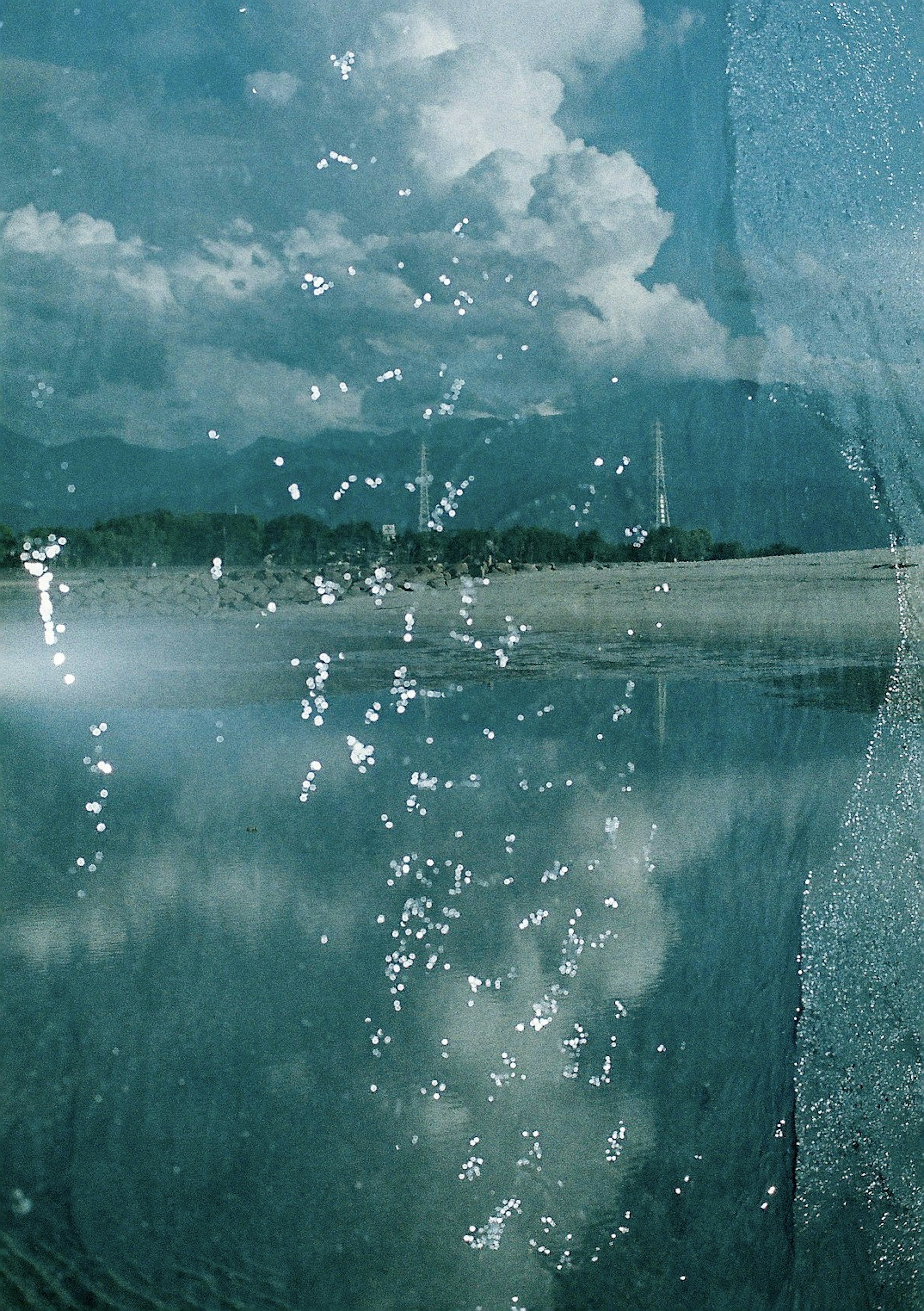 A tranquil lake reflecting clouds and mountains with water splashes