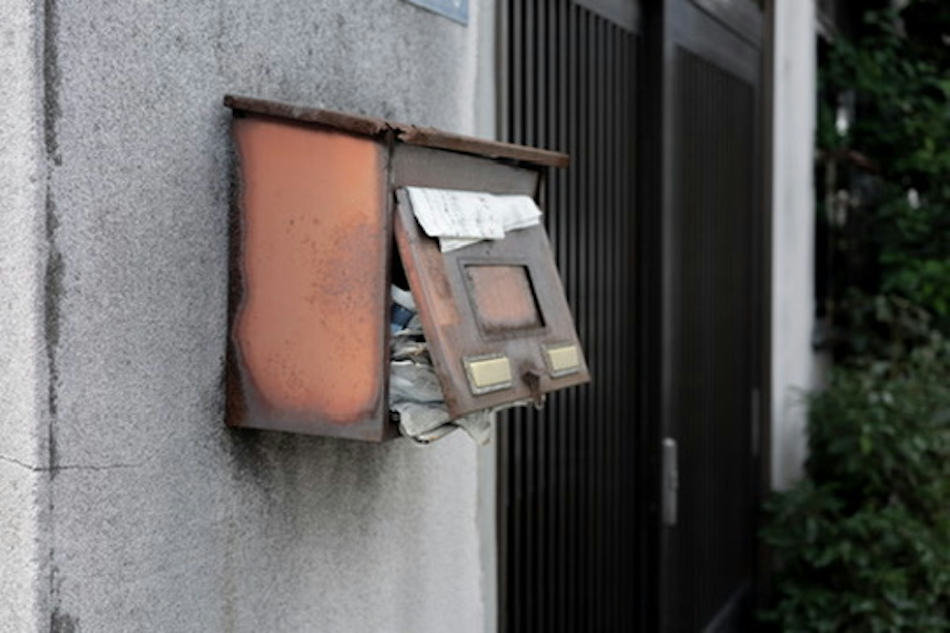 Une vieille boîte aux lettres fixée à un mur avec des papiers visibles à l'intérieur