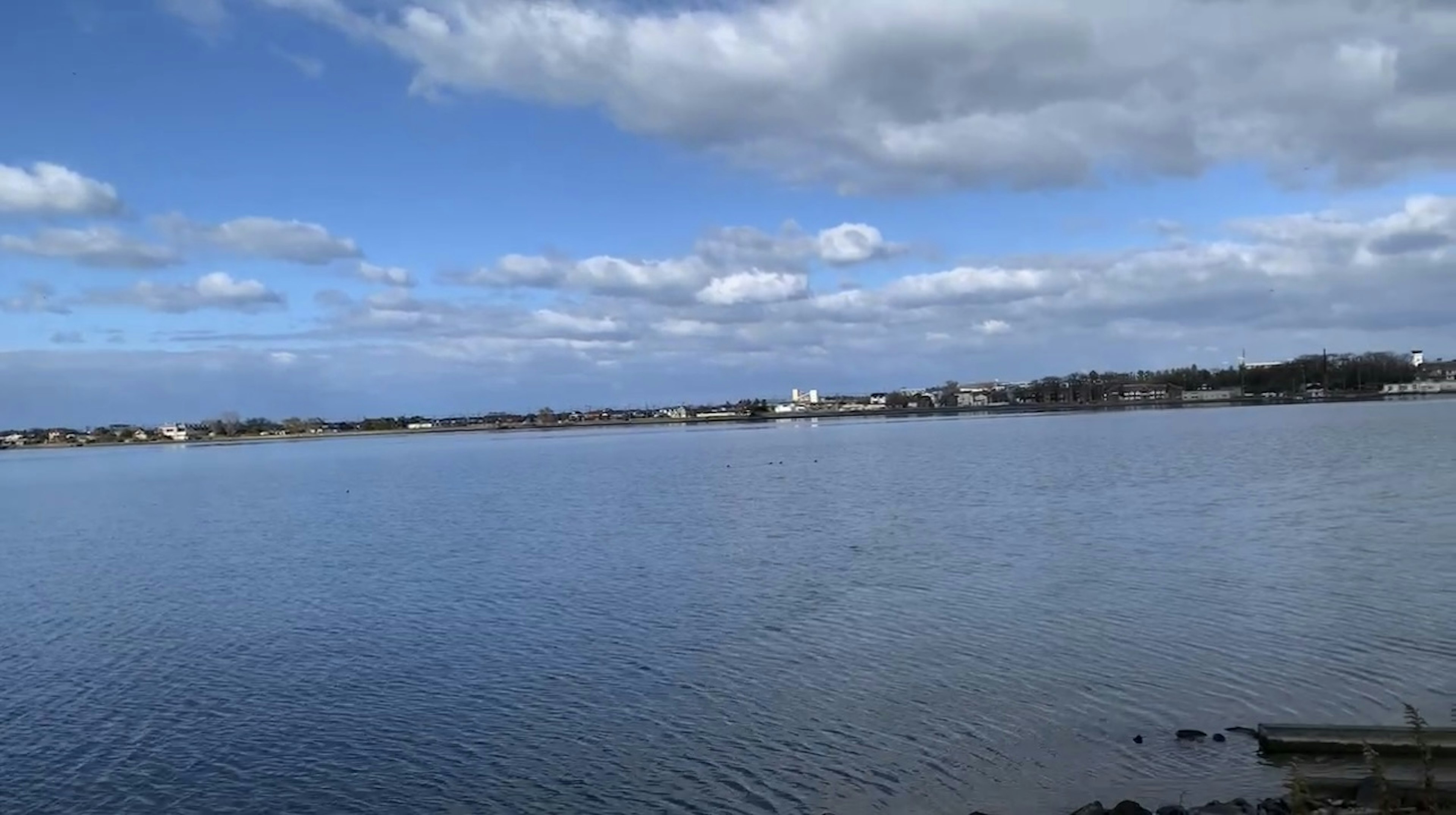 Agua tranquila que refleja un cielo azul con nubes blancas