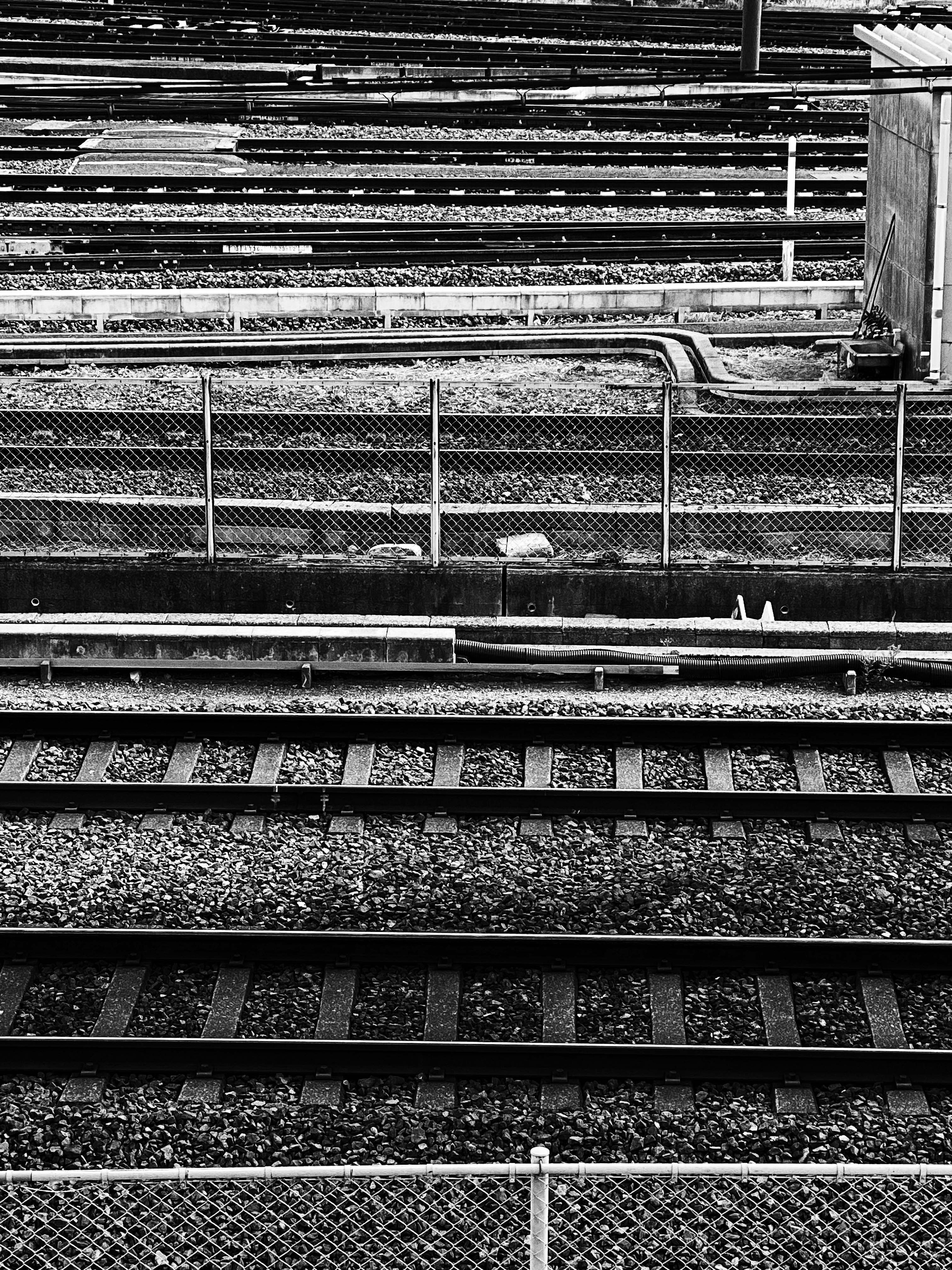 Vue en noir et blanc des voies ferrées et de la clôture