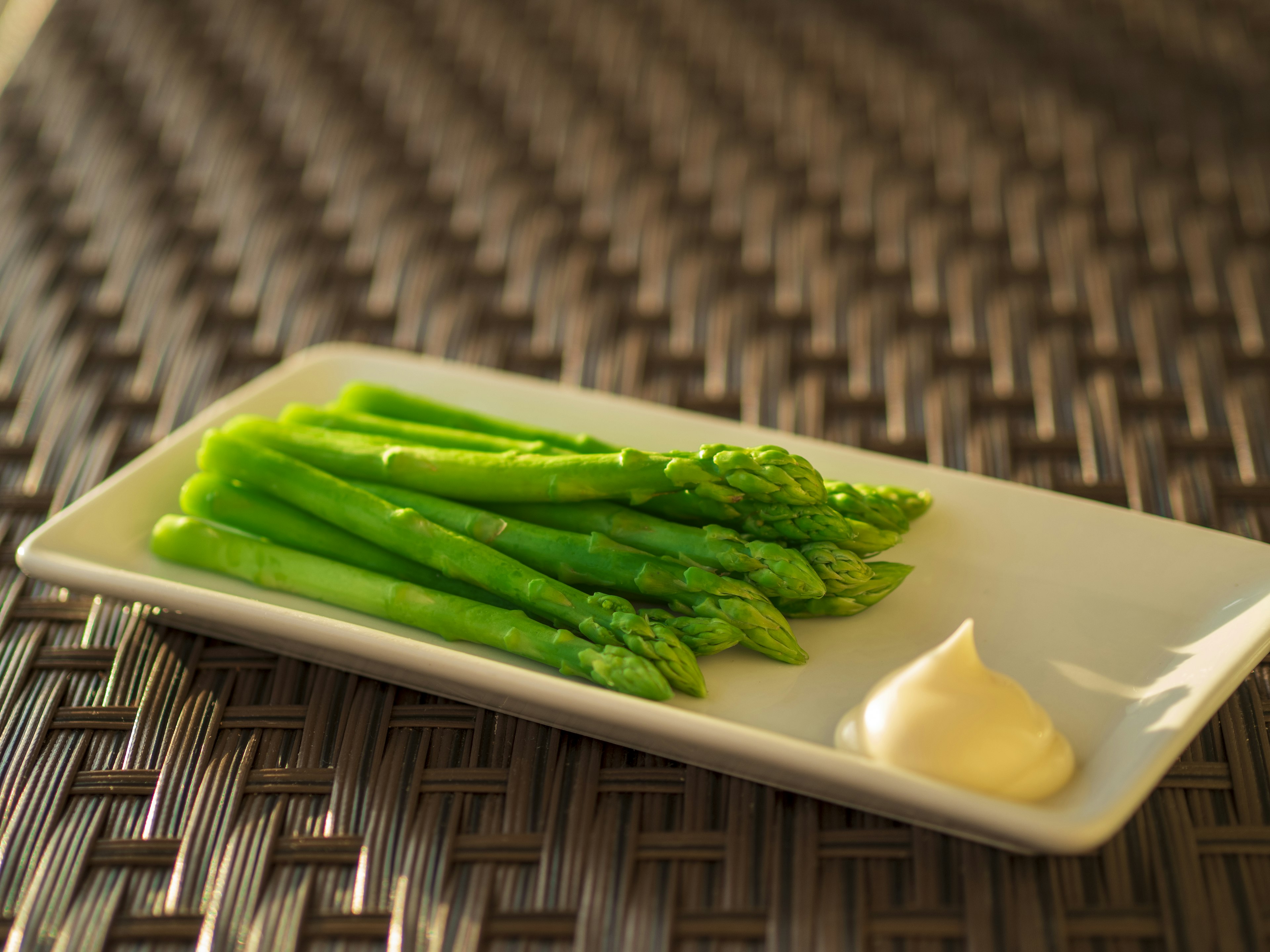 Fresh green asparagus on a white plate with creamy sauce