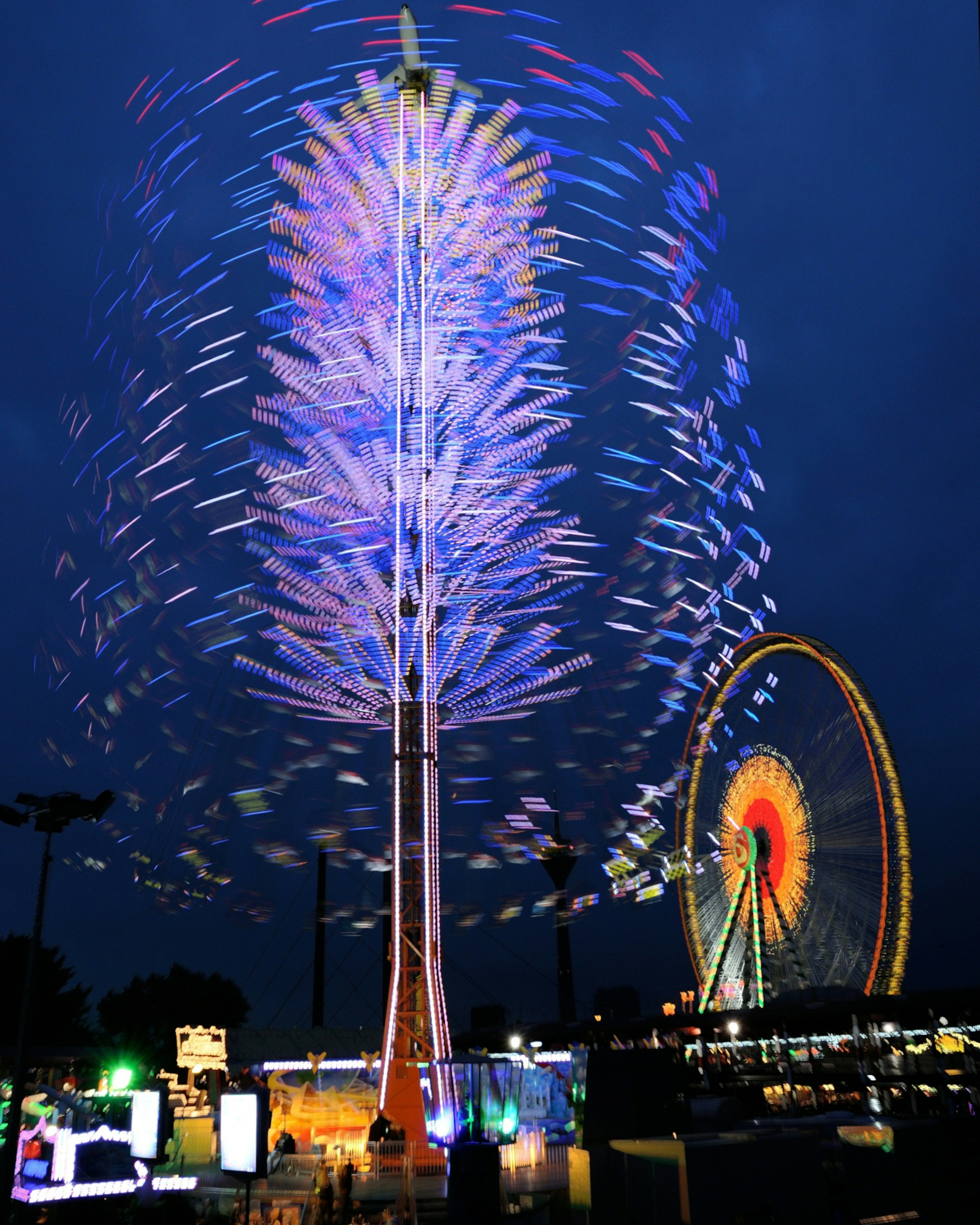 Colorful illuminated tower and Ferris wheel at night