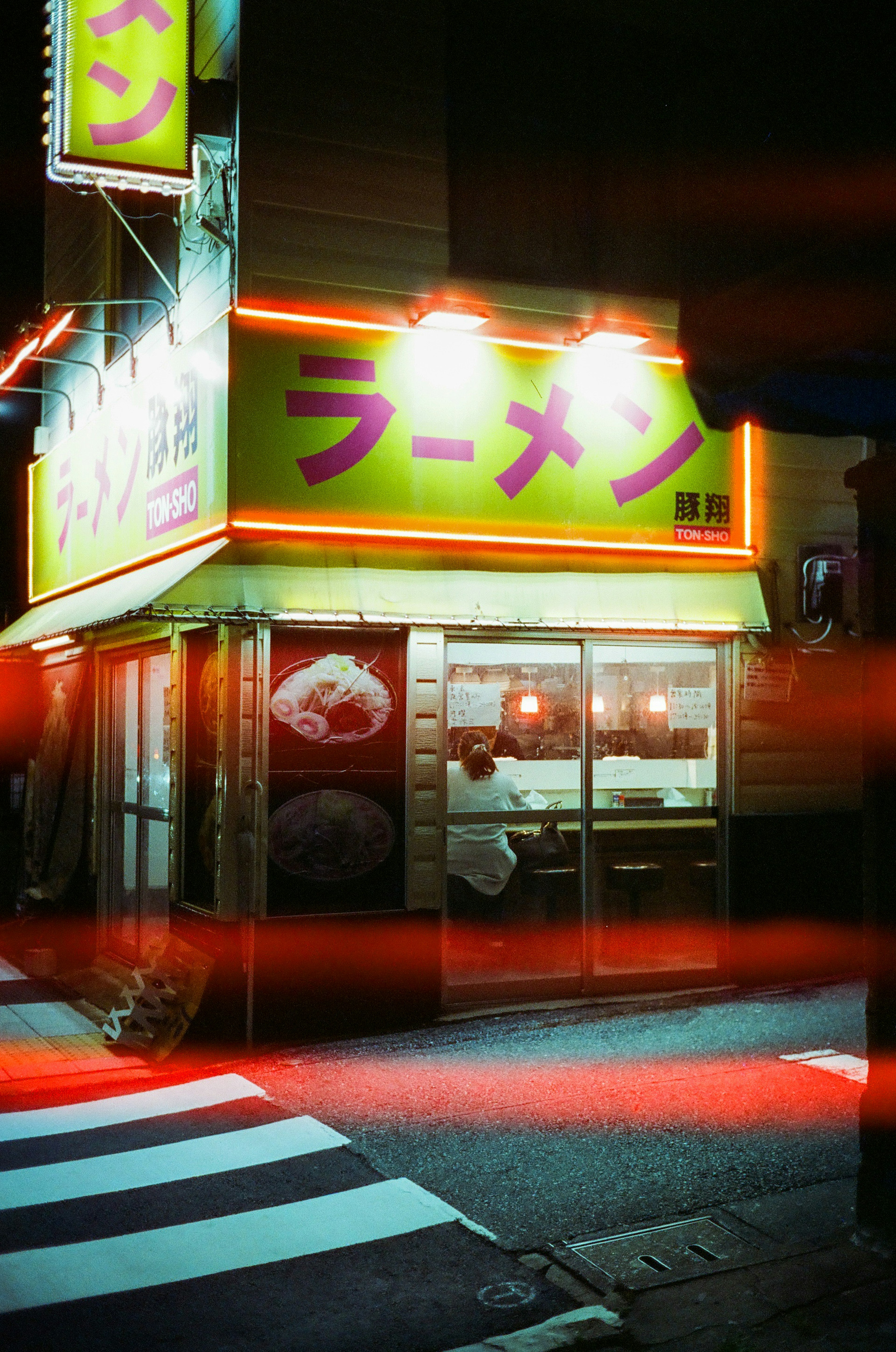 Brightly lit ramen shop exterior at night