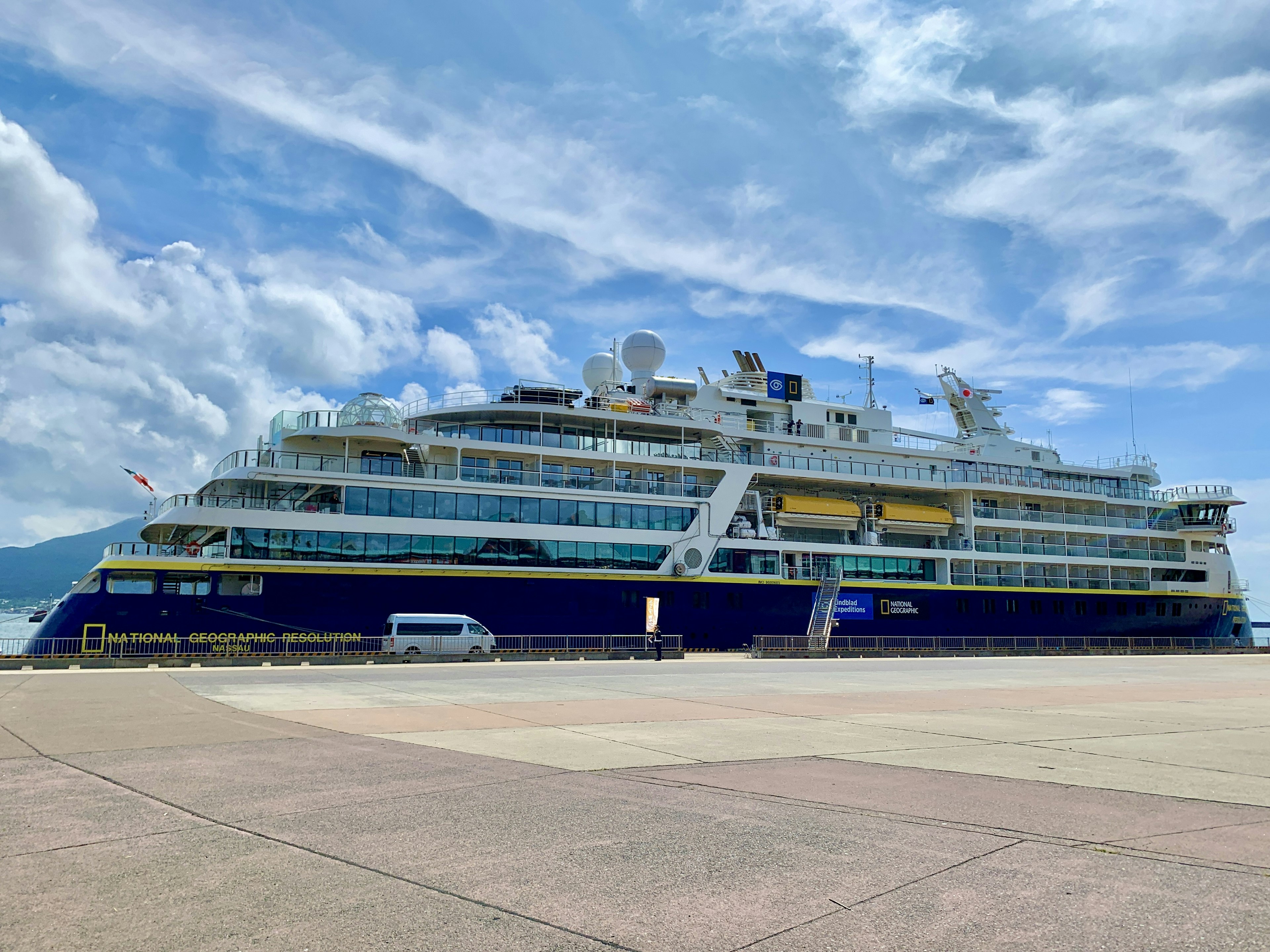 A blue cruise ship docked under a blue sky