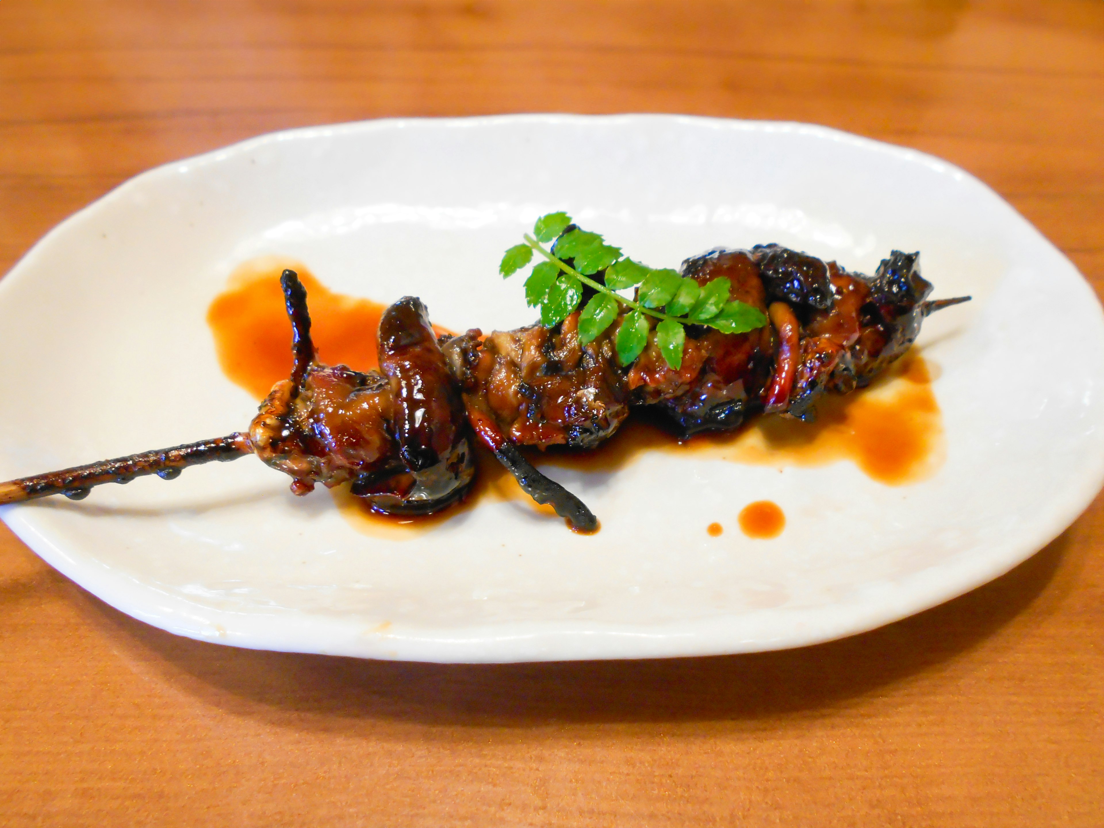 Brocheta de pollo a la parrilla servida en un plato blanco con guarnición