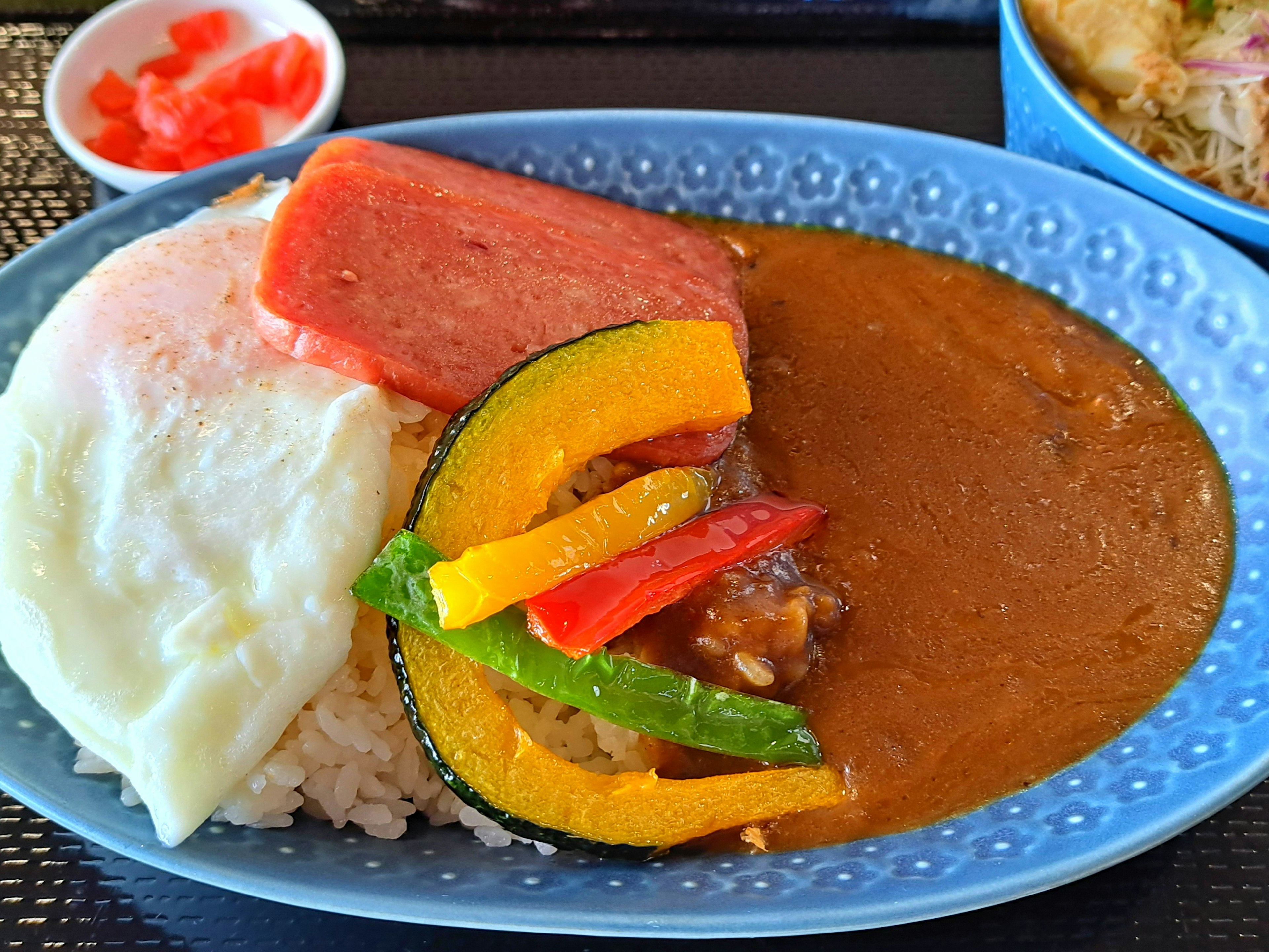 カレーライスのプレートに目玉焼きとスパムが添えられた料理