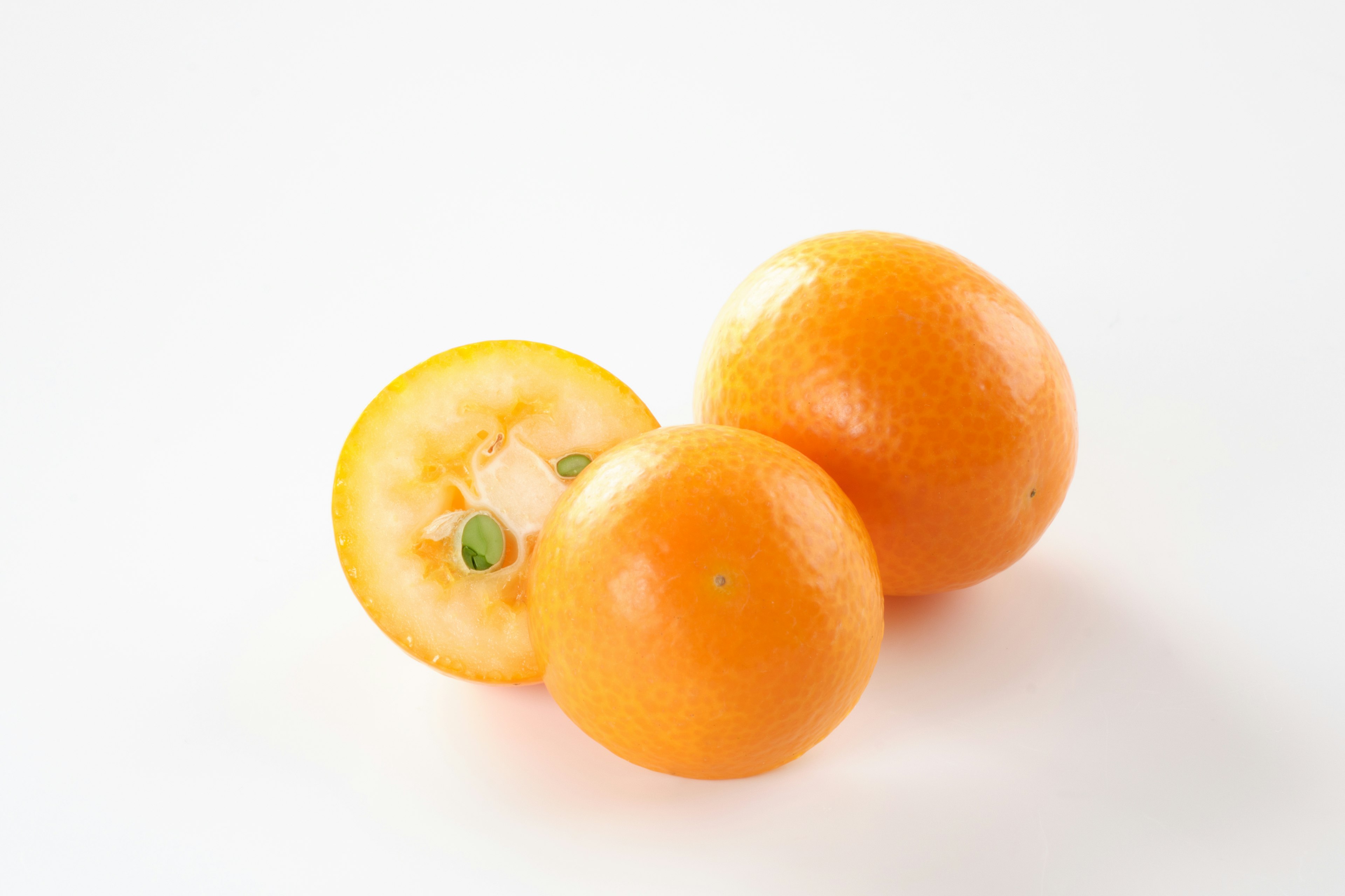 Two oranges with one sliced in half showing the interior on a white background