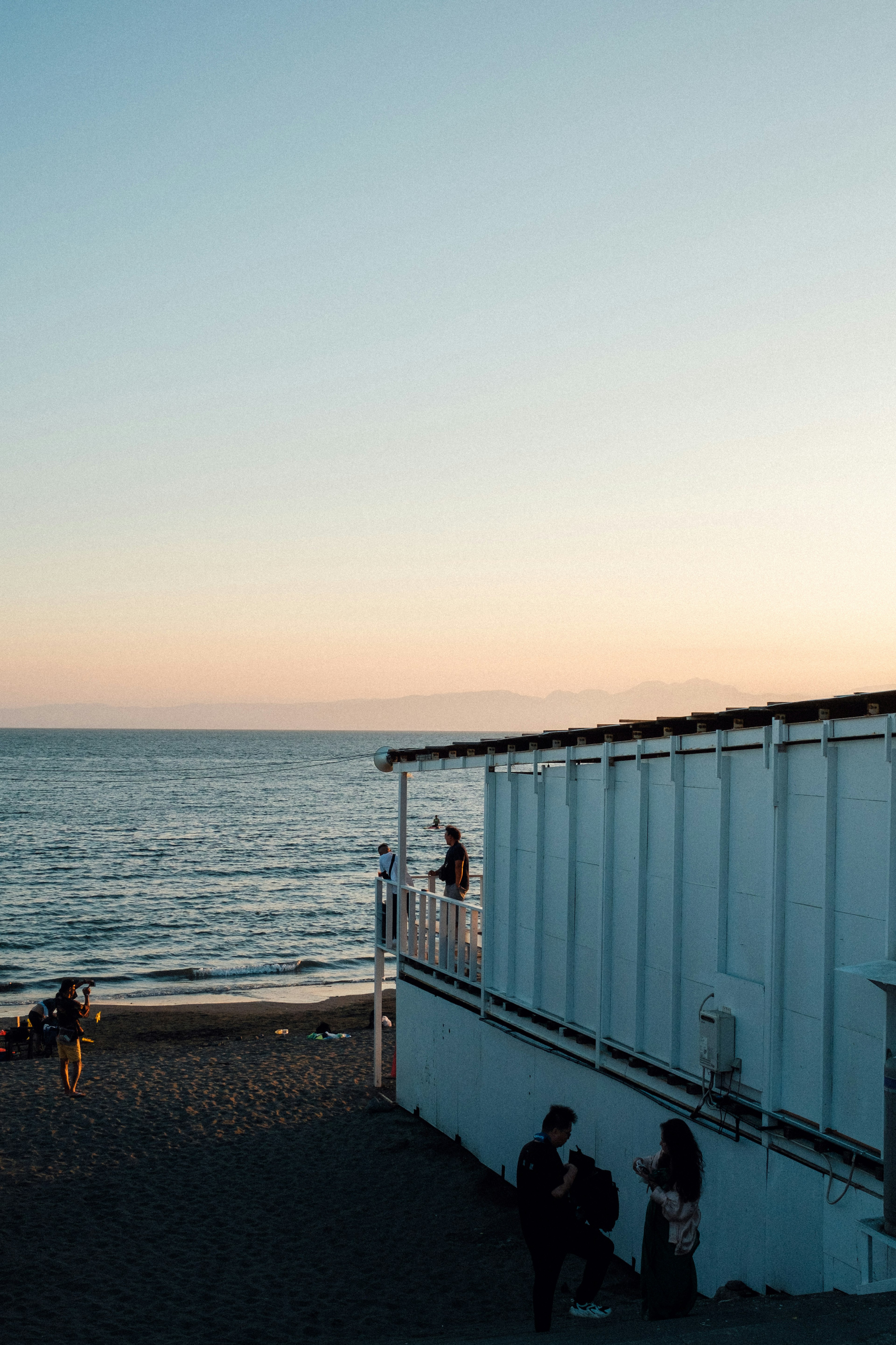 海の景色を背景にした白い建物と人々のシルエット