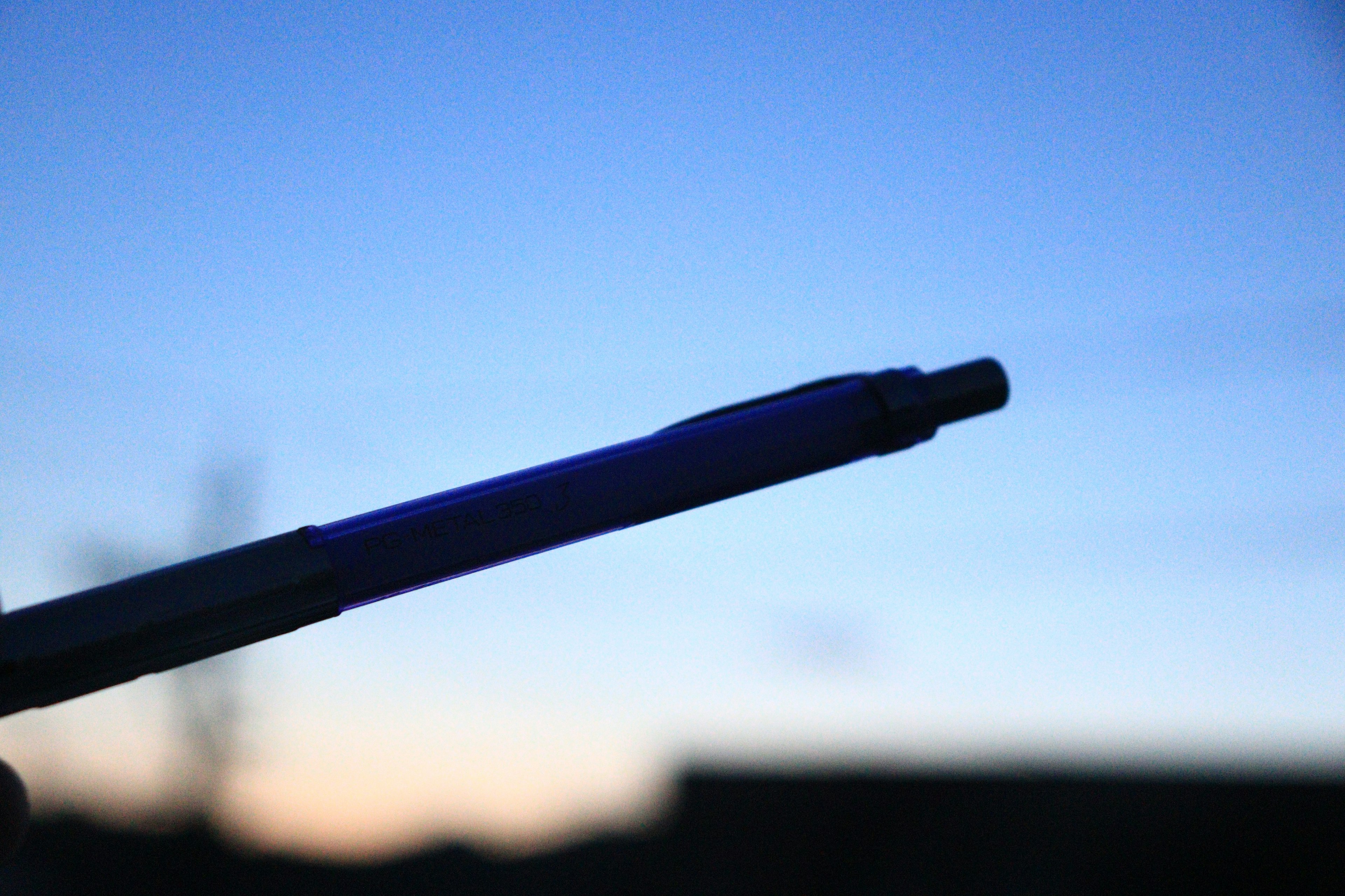 Silhouette of a pen against a blue sky