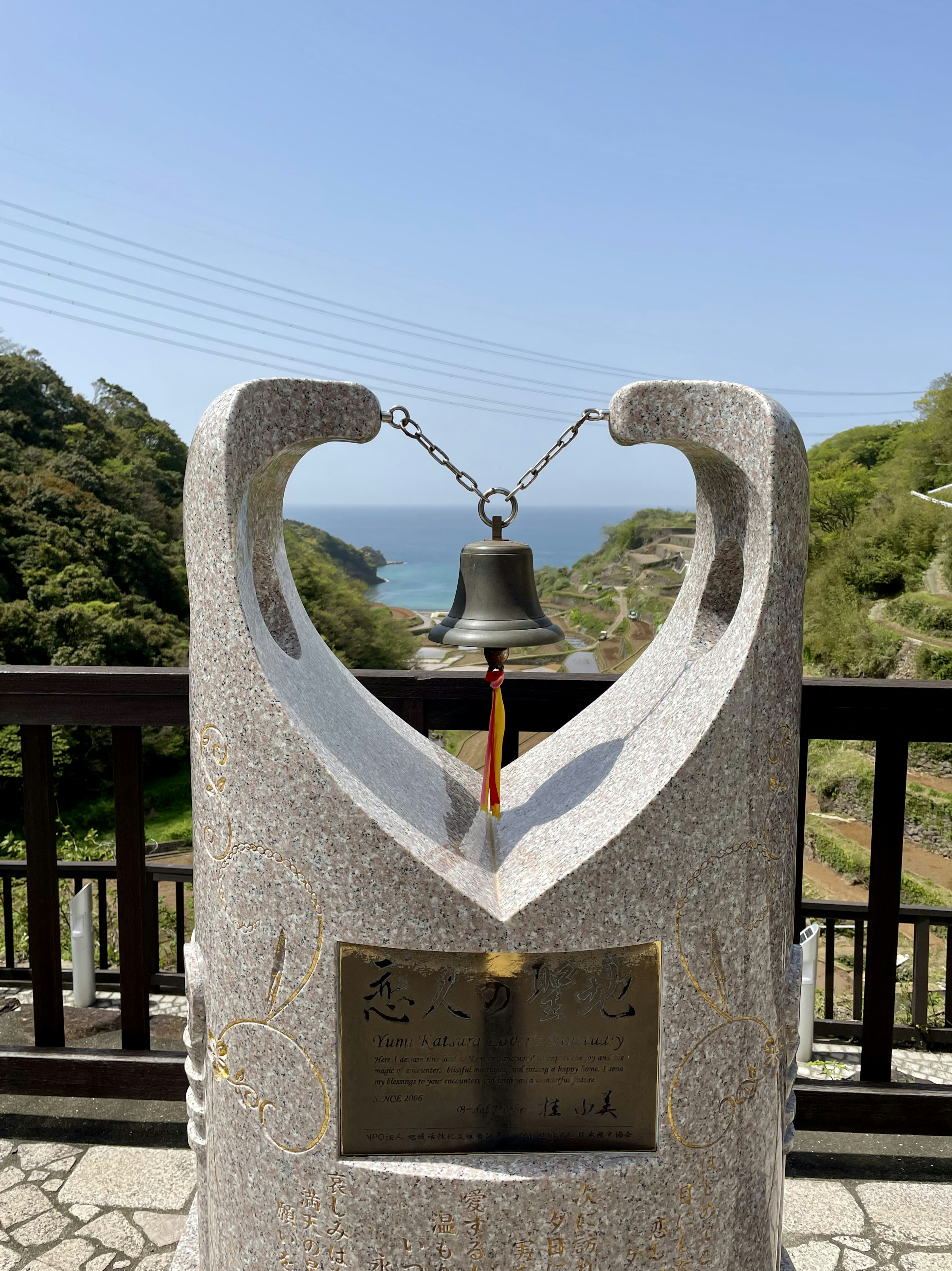 石の鐘と海の景色を背景にしたモニュメント